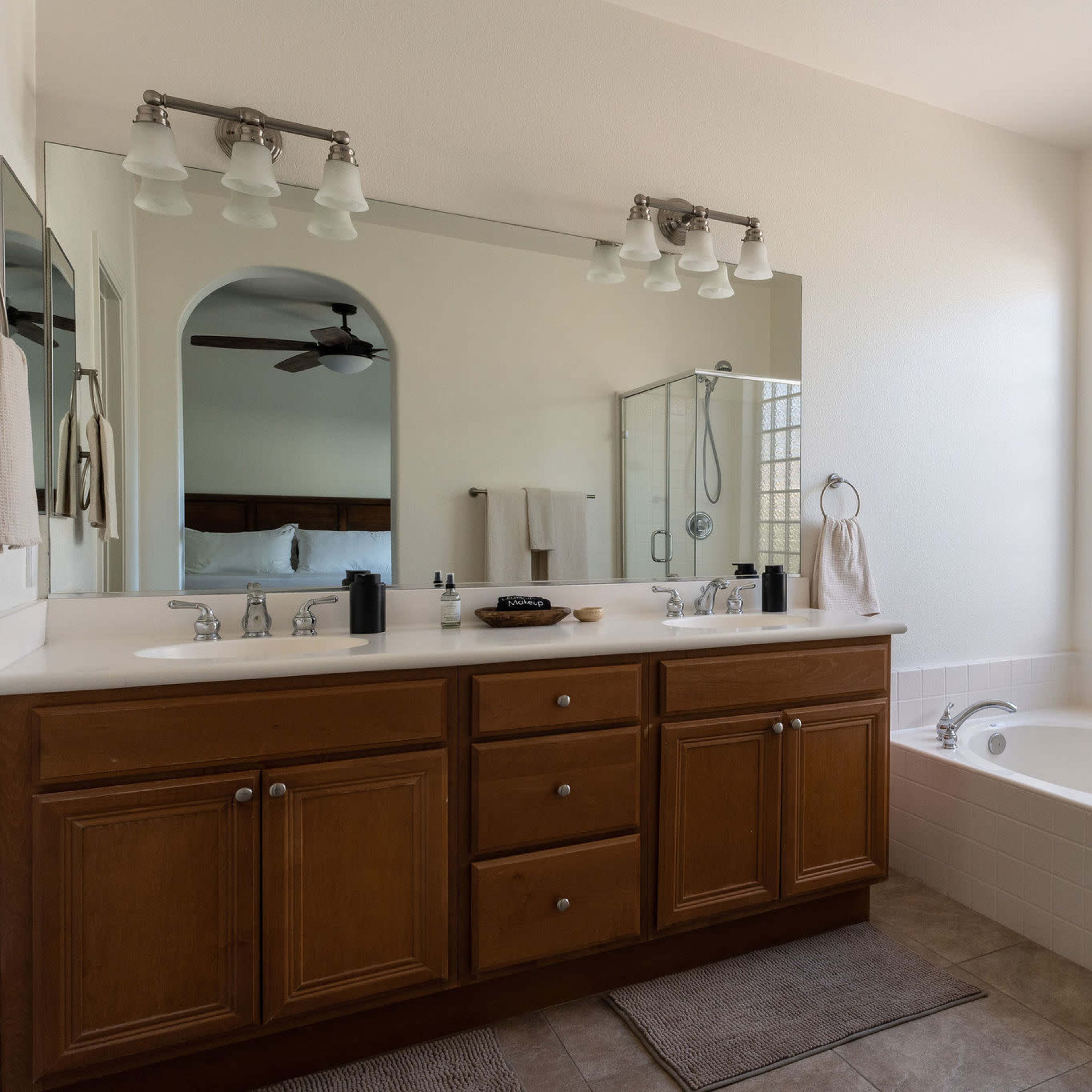 A bathroom with a double vanity, a glass-enclosed shower, and a separate bathtub beside a large window.