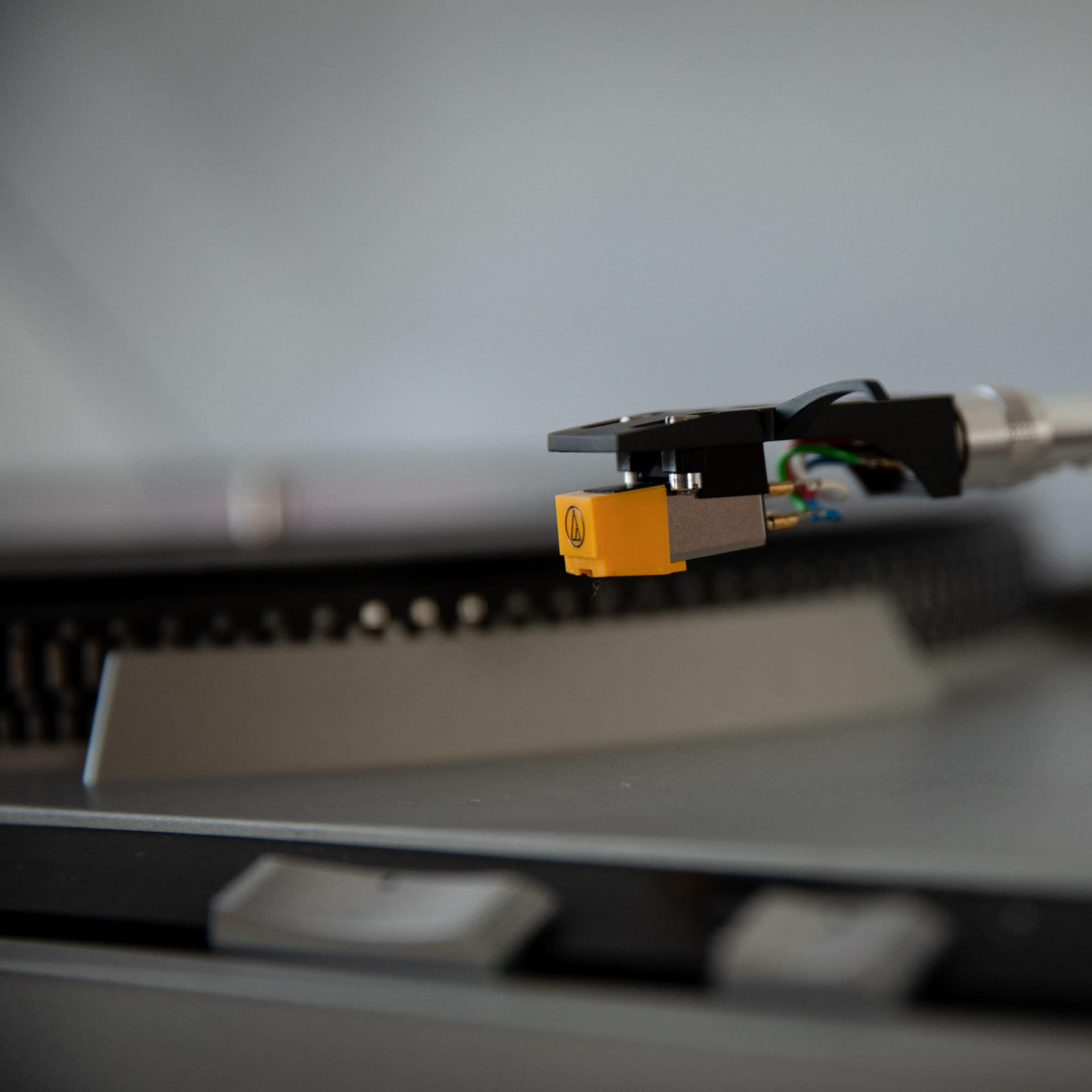 A close-up of a turntable's tonearm with a stylus positioned above a vinyl record.