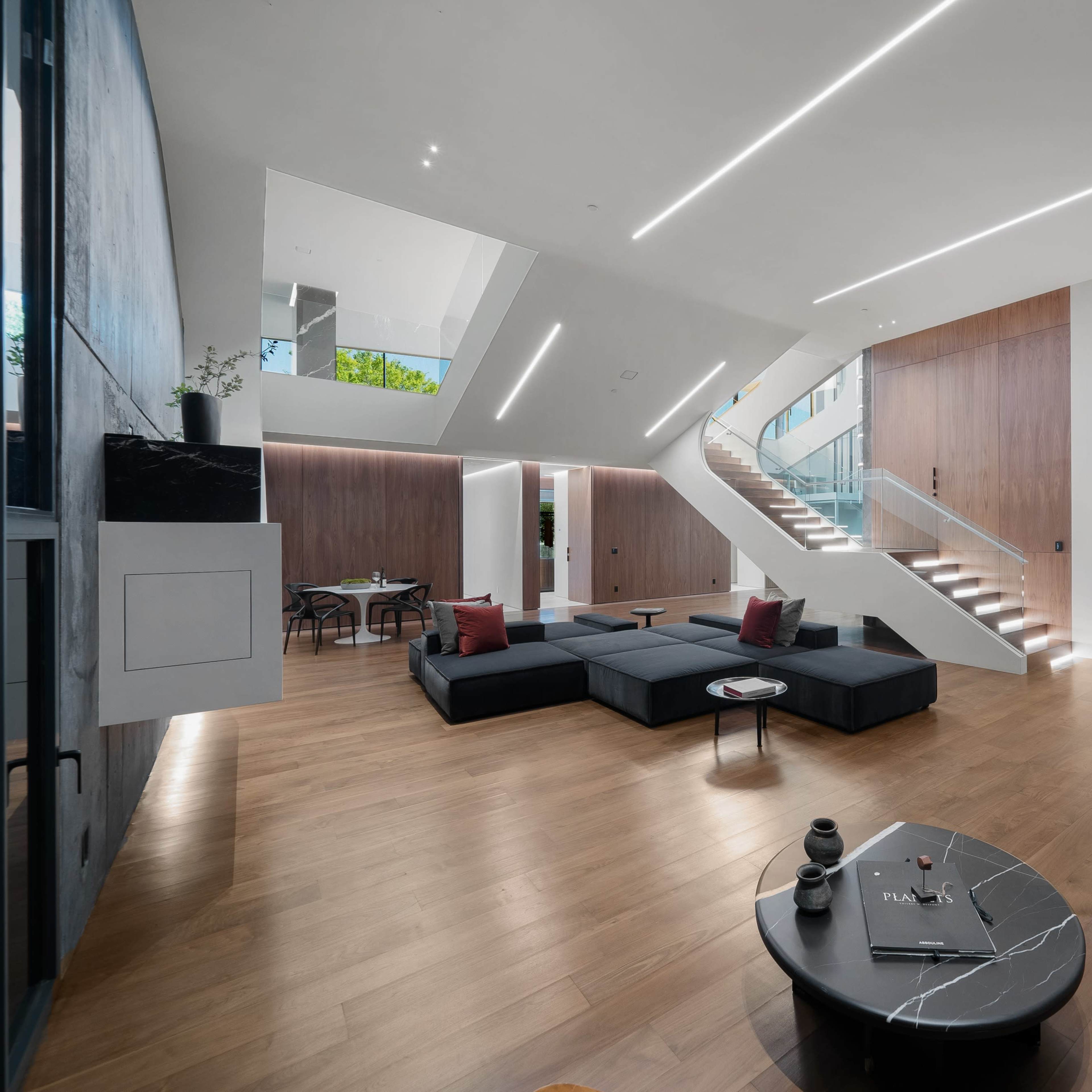 A modern living room with a dark sectional sofa, a round coffee table, and a staircase leading to an upper level.