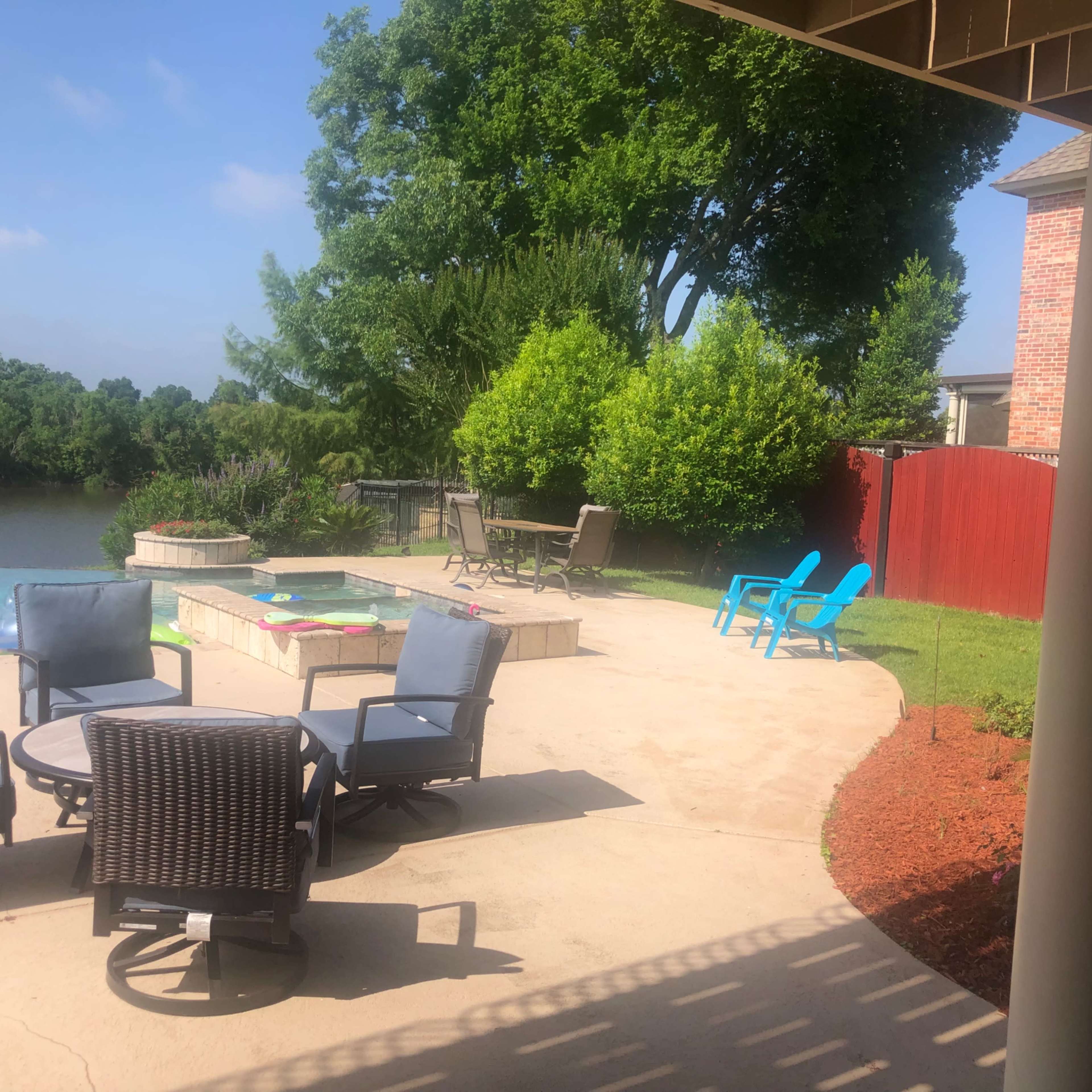 A backyard with patio furniture, a swimming pool, and a scenic view of a body of water and greenery.