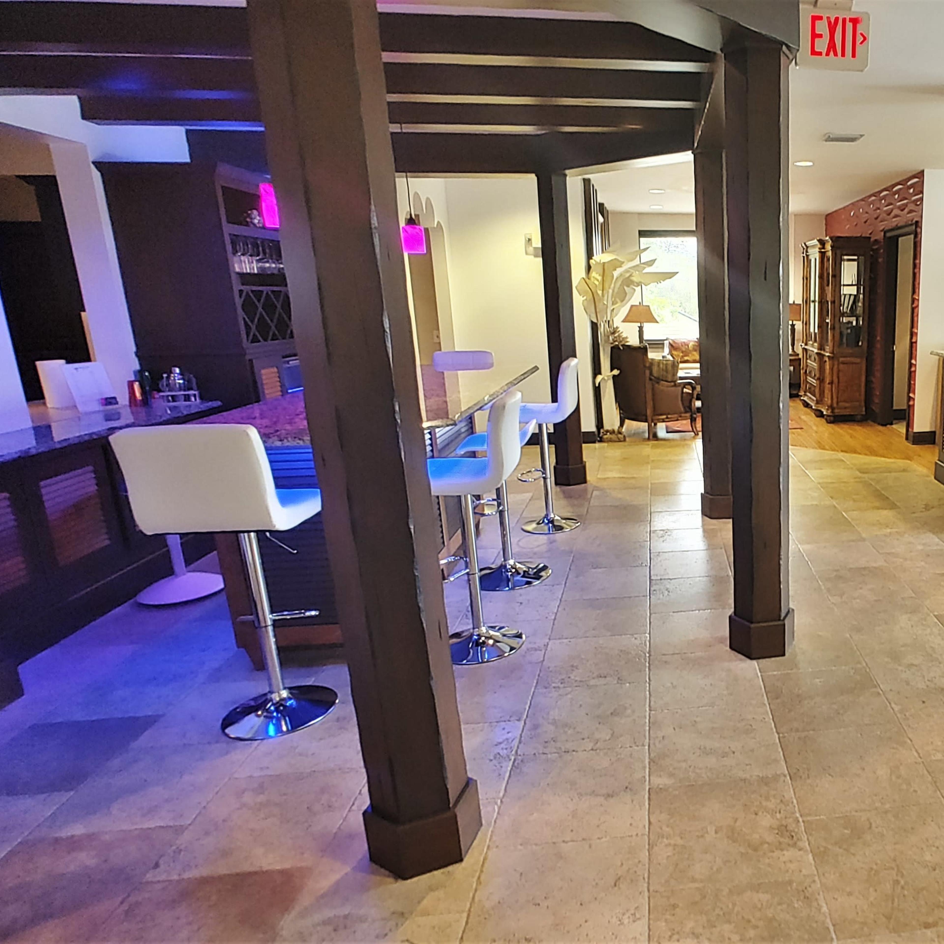 A spacious interior with a bar area on the left and a reception desk on the right, featuring wooden beams and tile flooring.