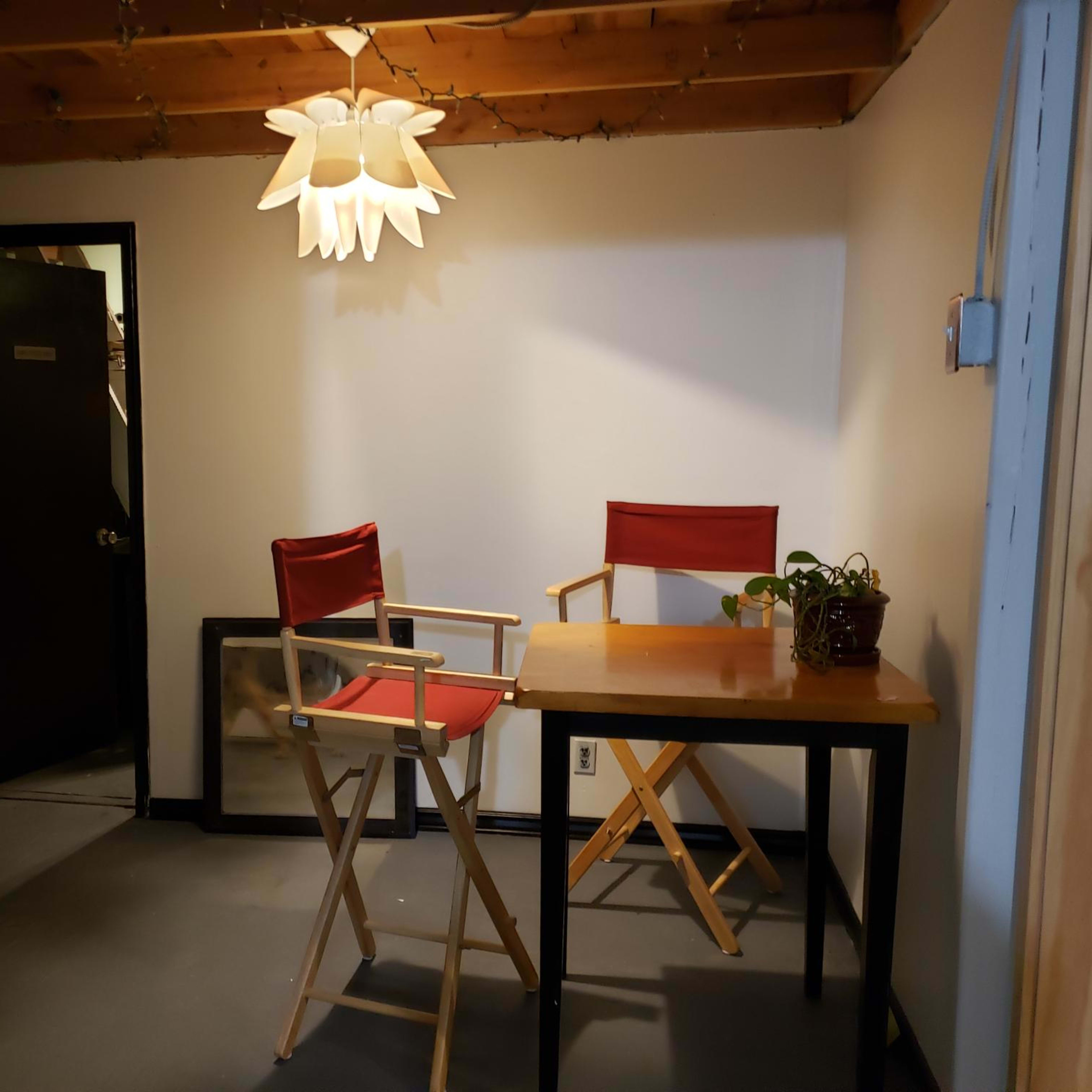 The scene shows a small room with a table, two chairs, a plant, and a pendant light hanging from the ceiling.