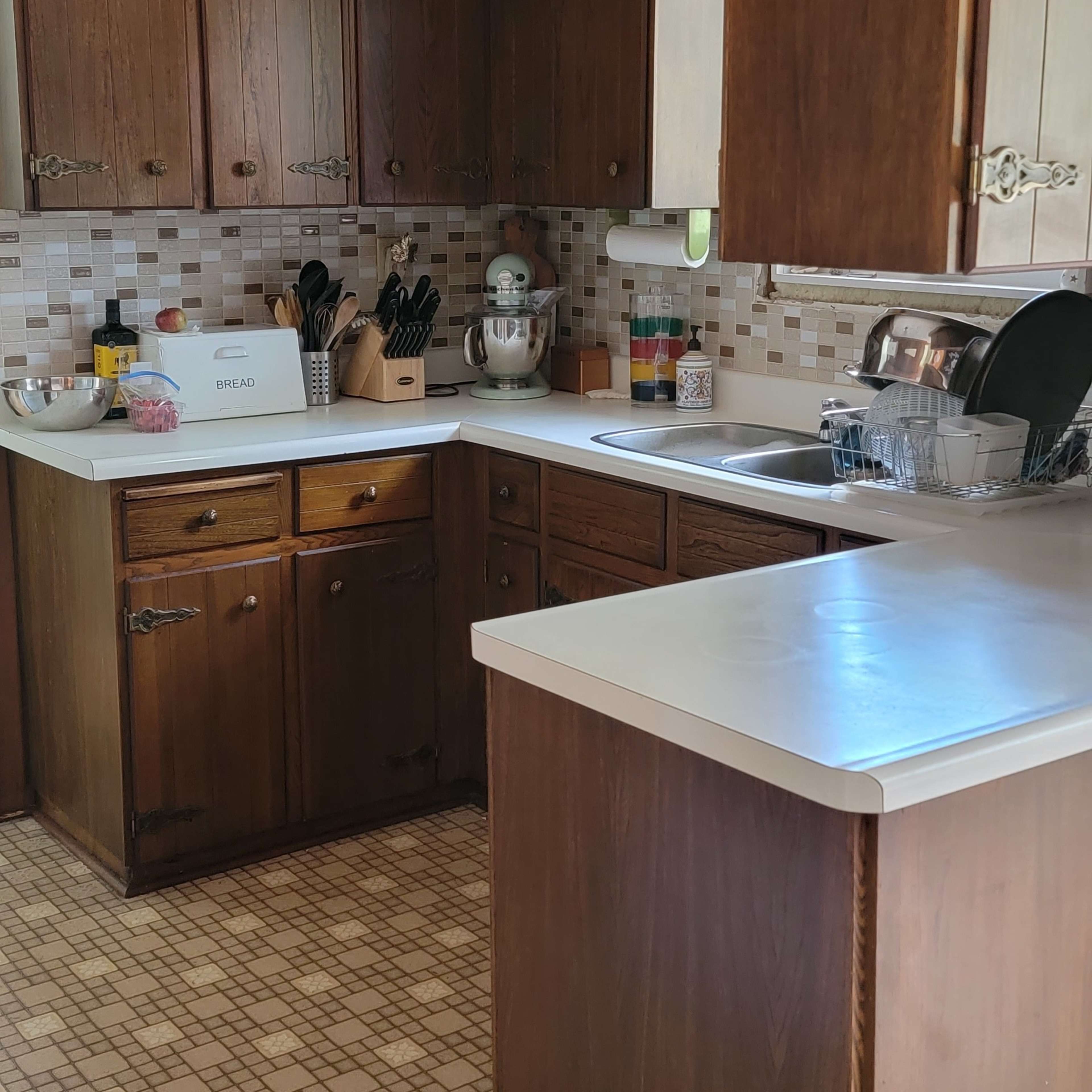 A kitchen with wooden cabinets, a countertop, and a checkered floor pattern.