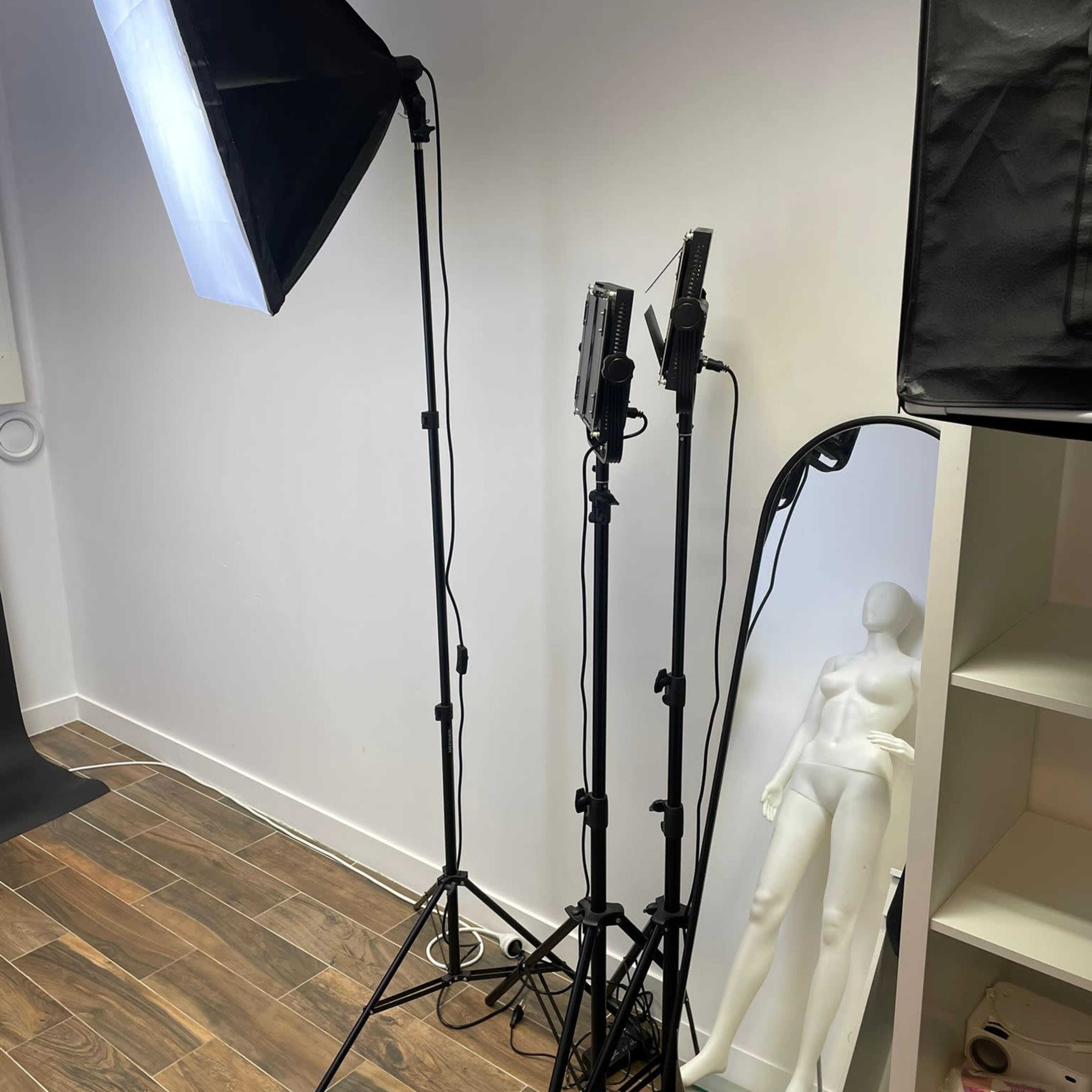 A photography setup with two softbox lights and a mannequin next to a full-length mirror against a white wall.
