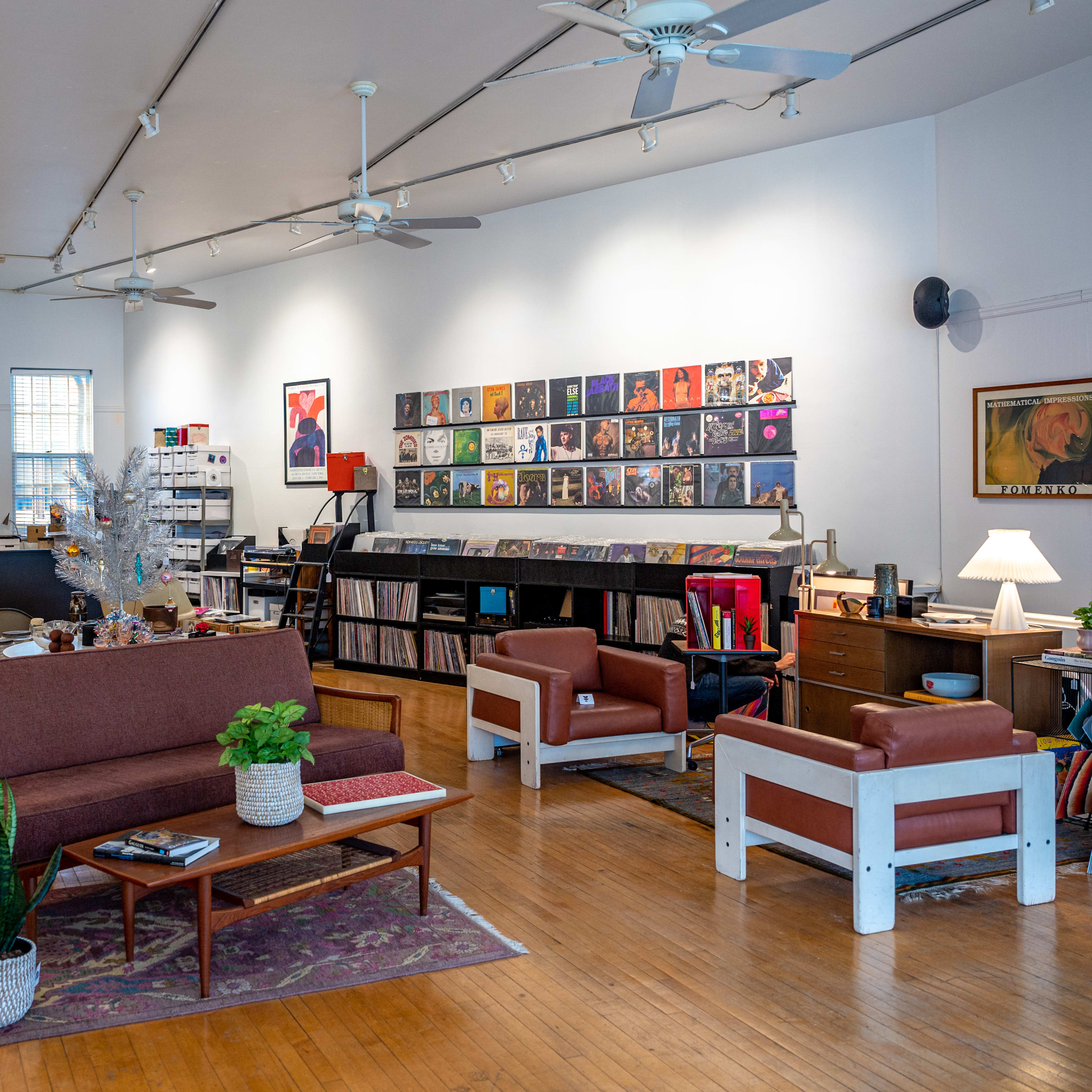 A spacious record store with shelves of vinyl records, seating areas, and a service counter in the background.