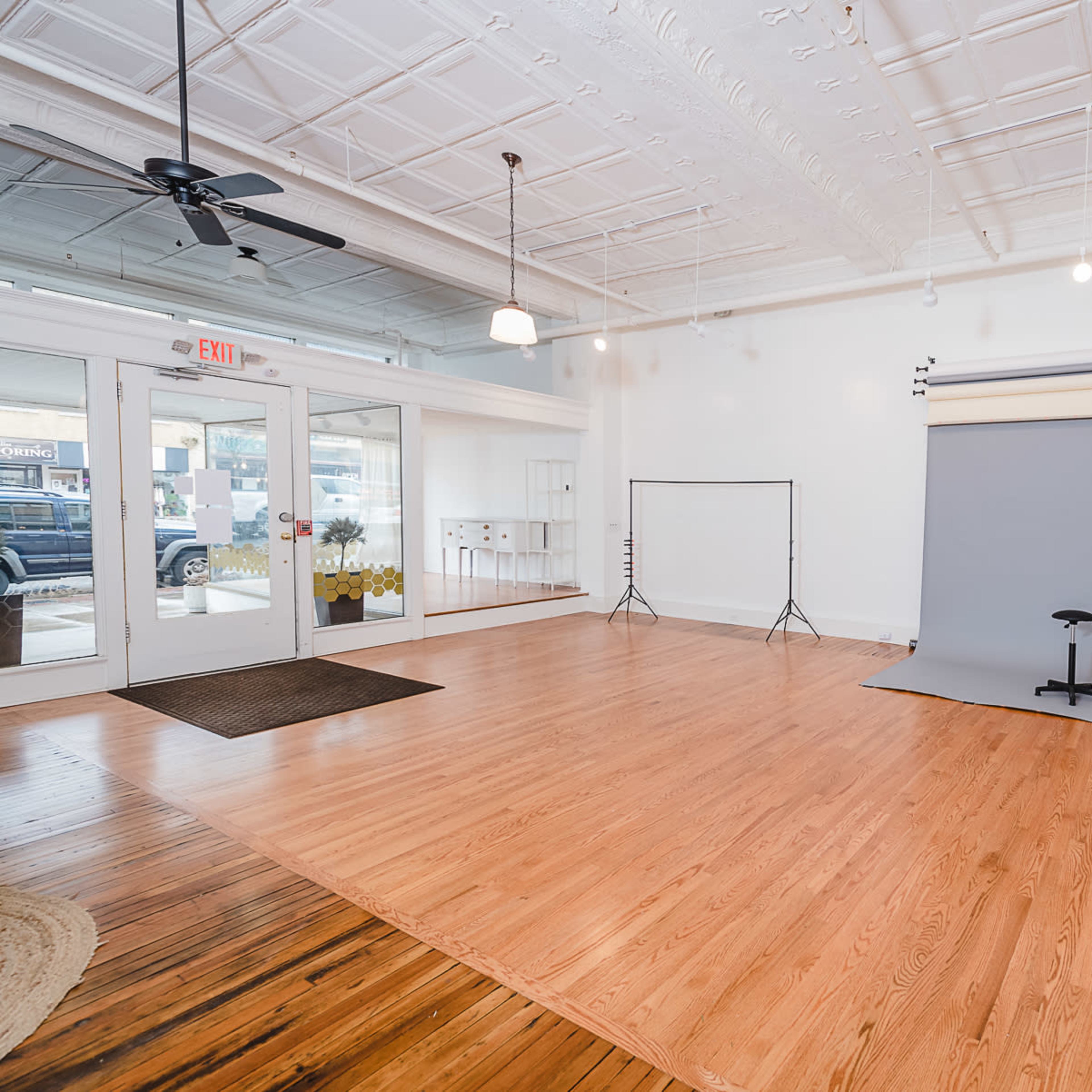 A spacious indoor photography studio featuring a gray backdrop, wooden floors, and a blue couch.