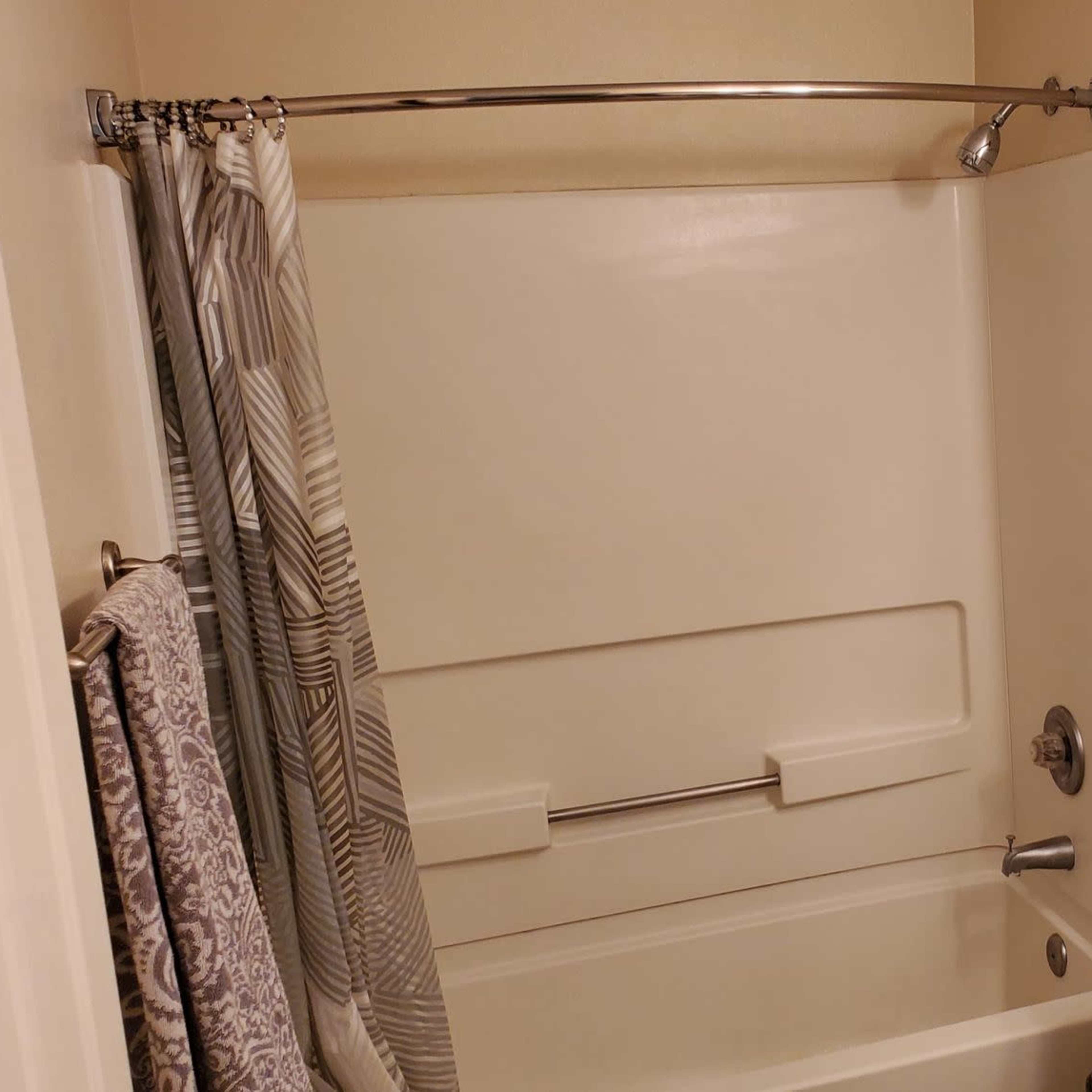 A bathroom featuring a bathtub with a shower curtain, a toilet, and a sink with a mirror above it.