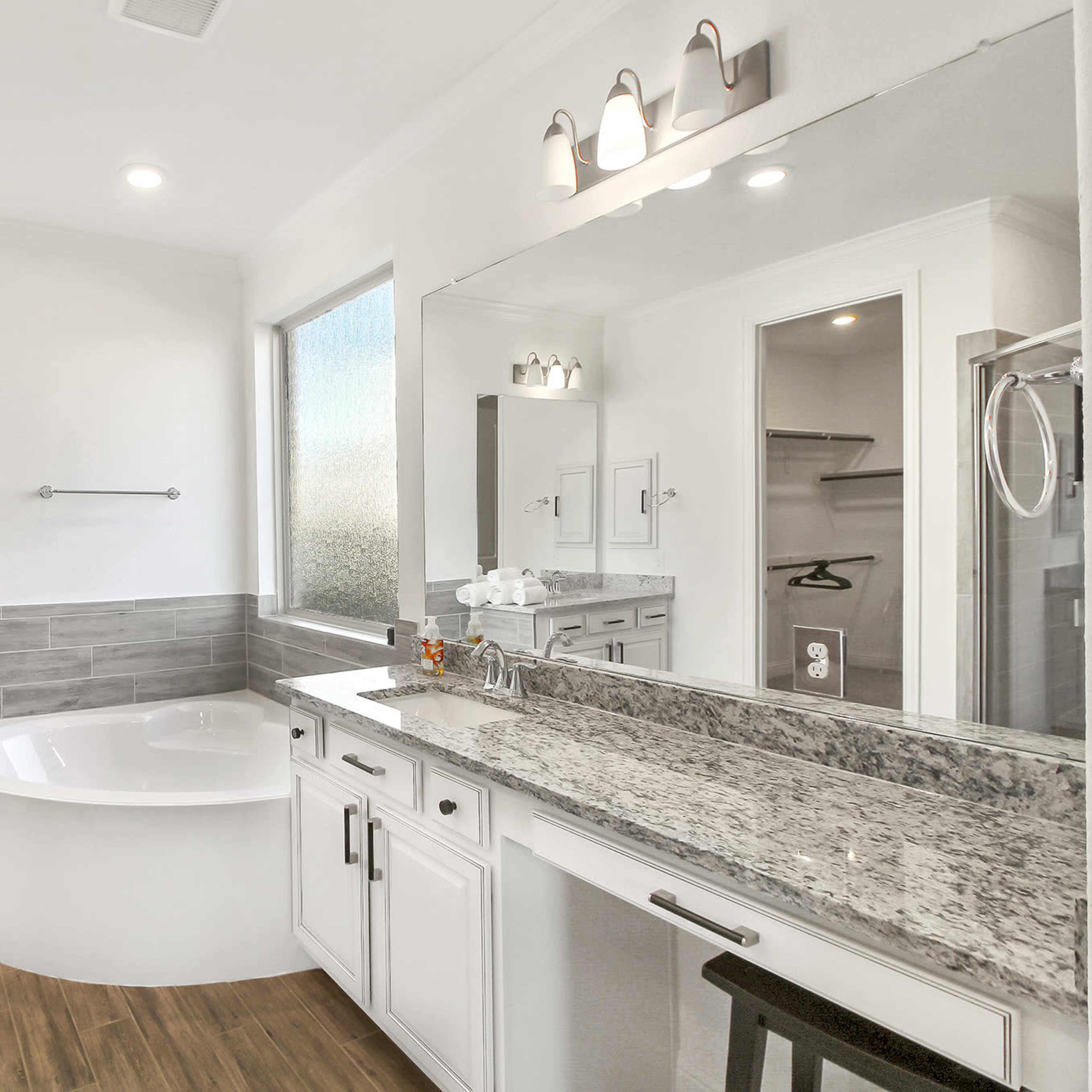 A modern bathroom featuring dual sinks, a large mirror, a freestanding bathtub, and a separate shower area.