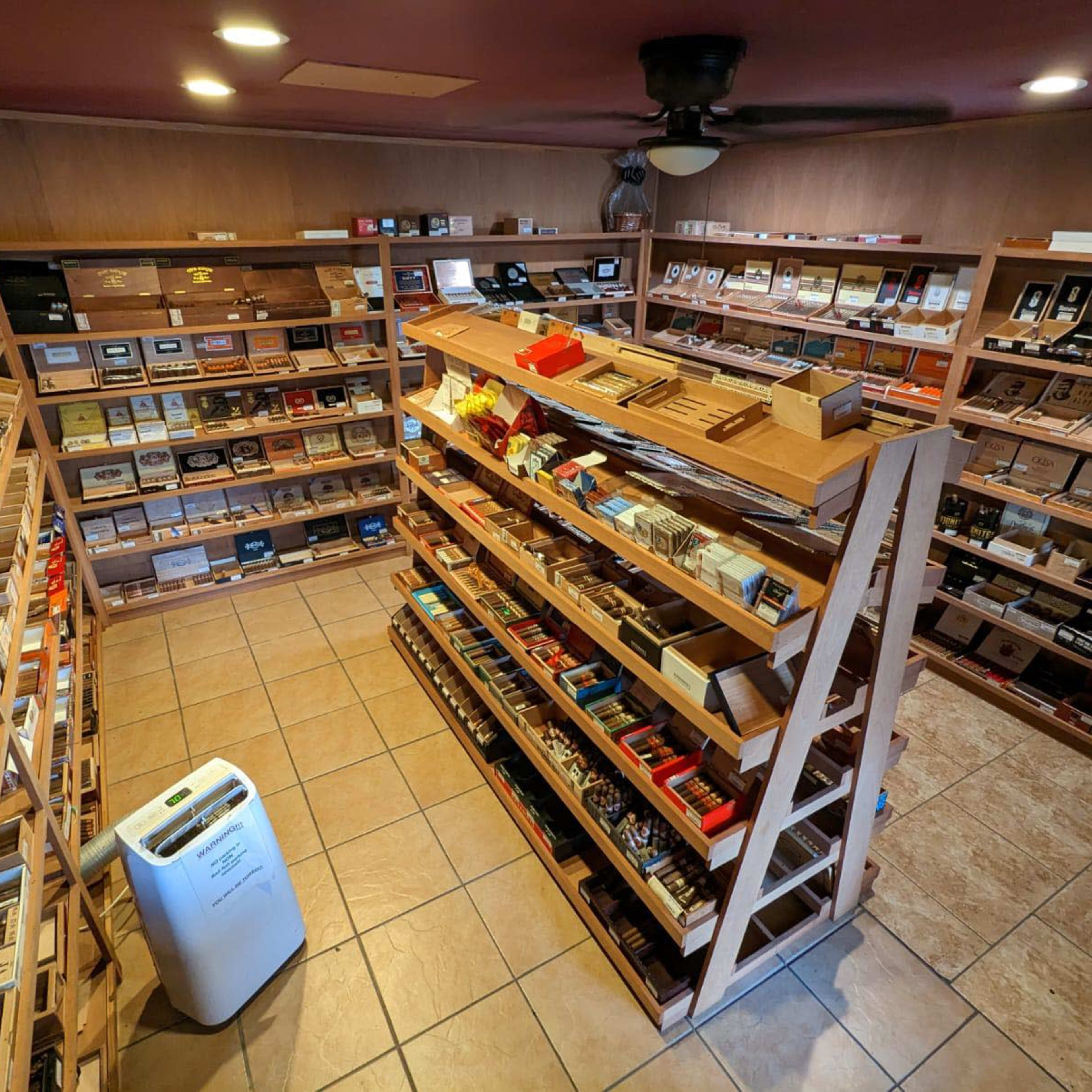 A well-organized cigar store with wooden shelves displaying a variety of cigar boxes in a tiled room.