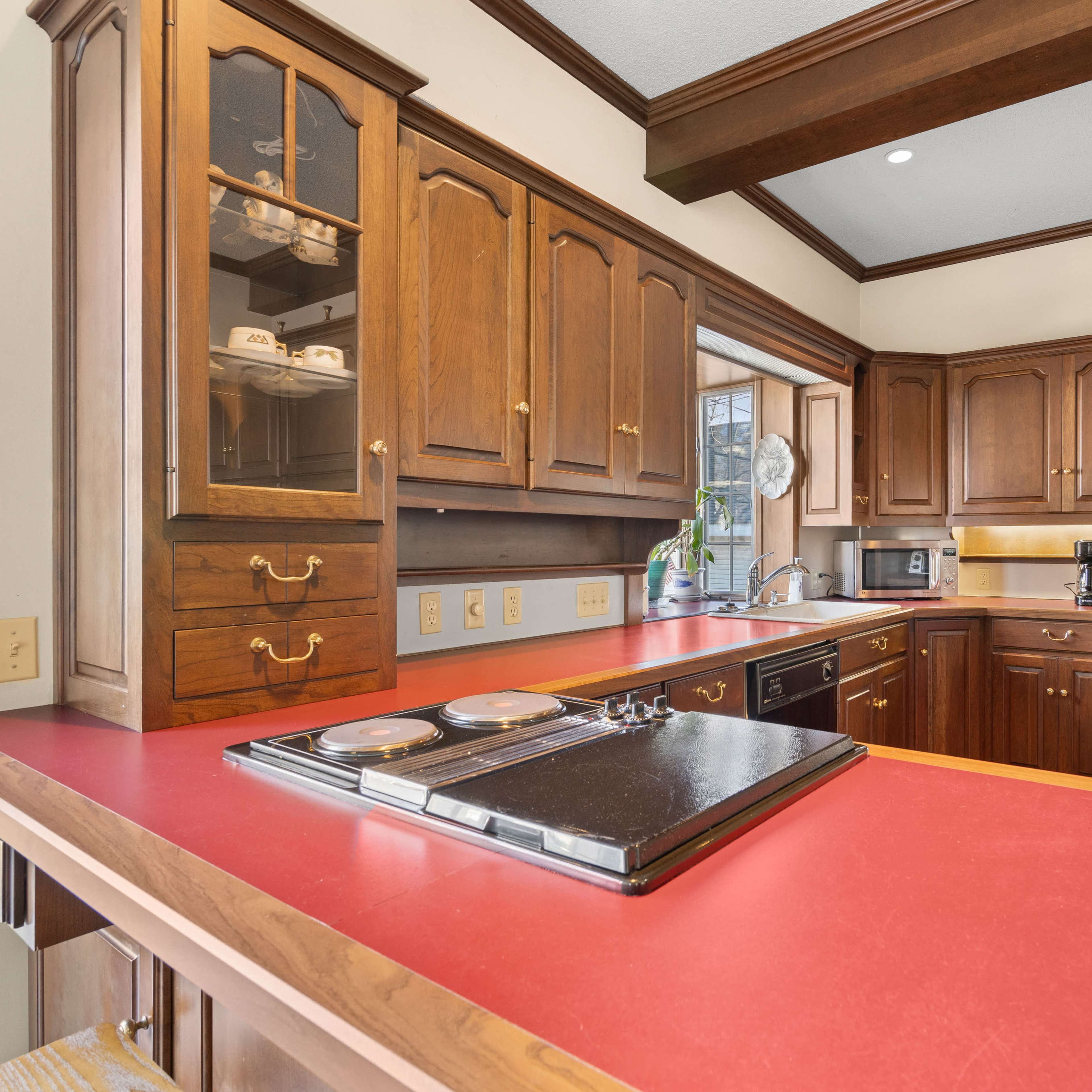 A kitchen featuring wooden cabinets, a red countertop, and stainless steel appliances.