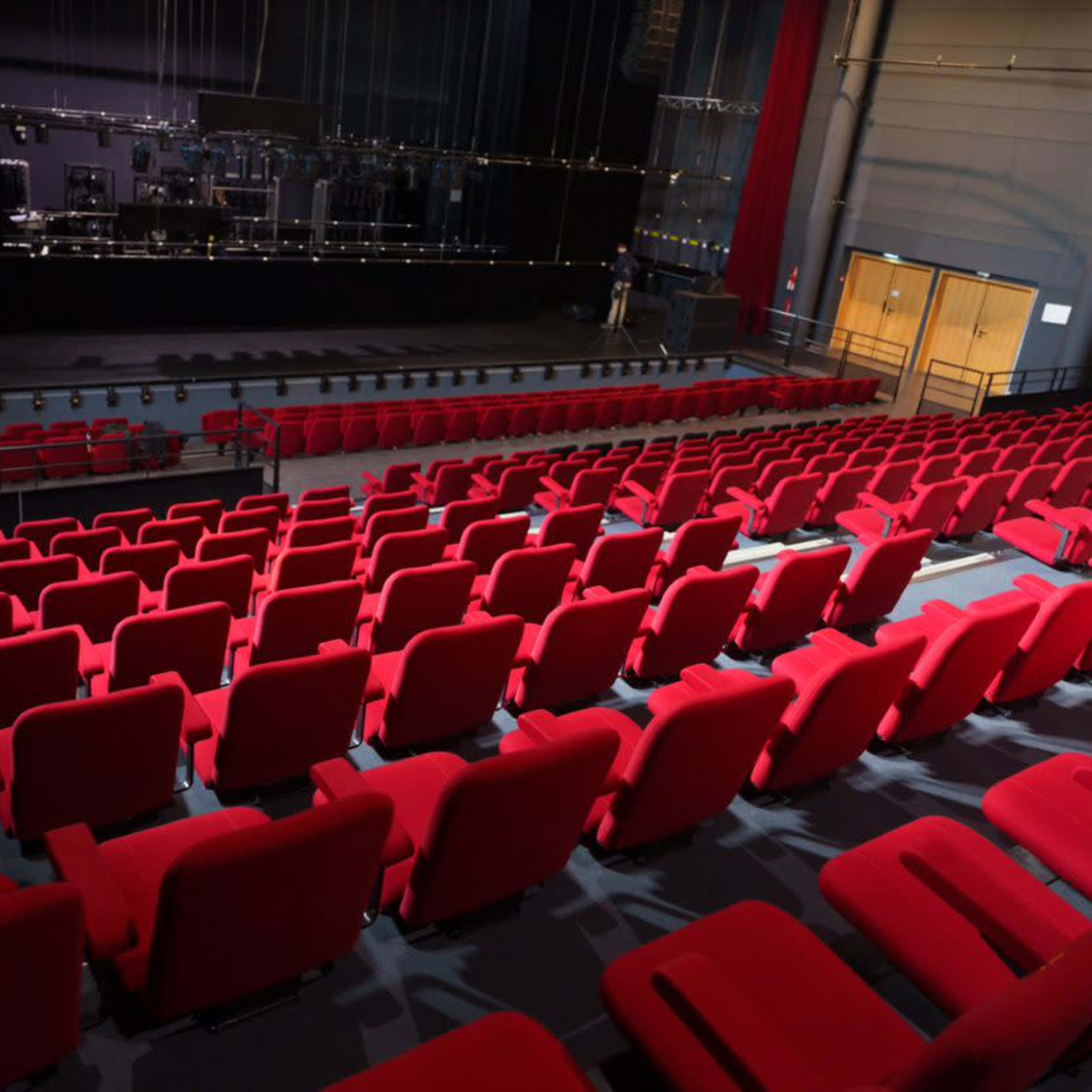 A stage and an audience area filled with red chairs in a theater setting.