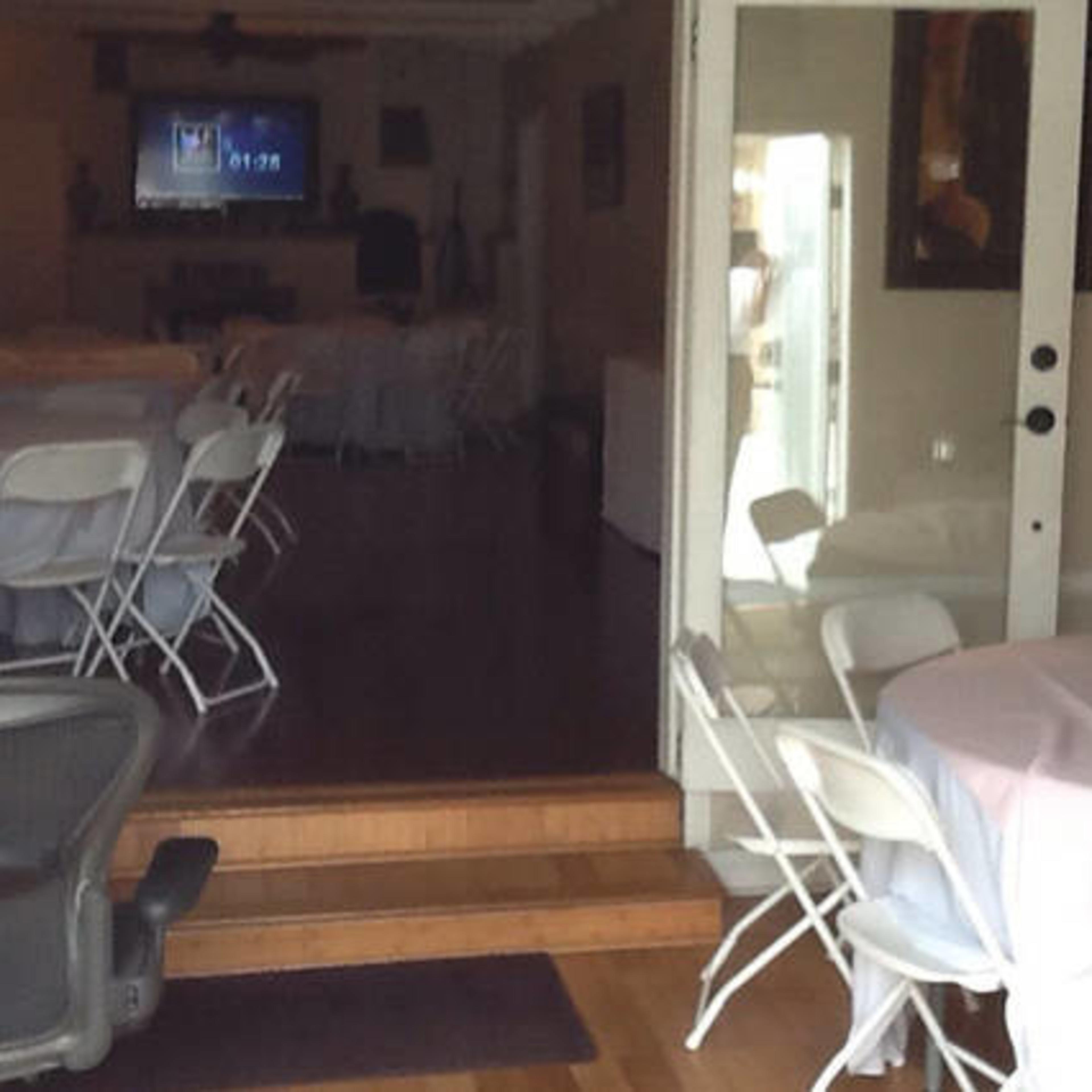 A doorway leads into a room set up with tables and chairs, visible in the background.
