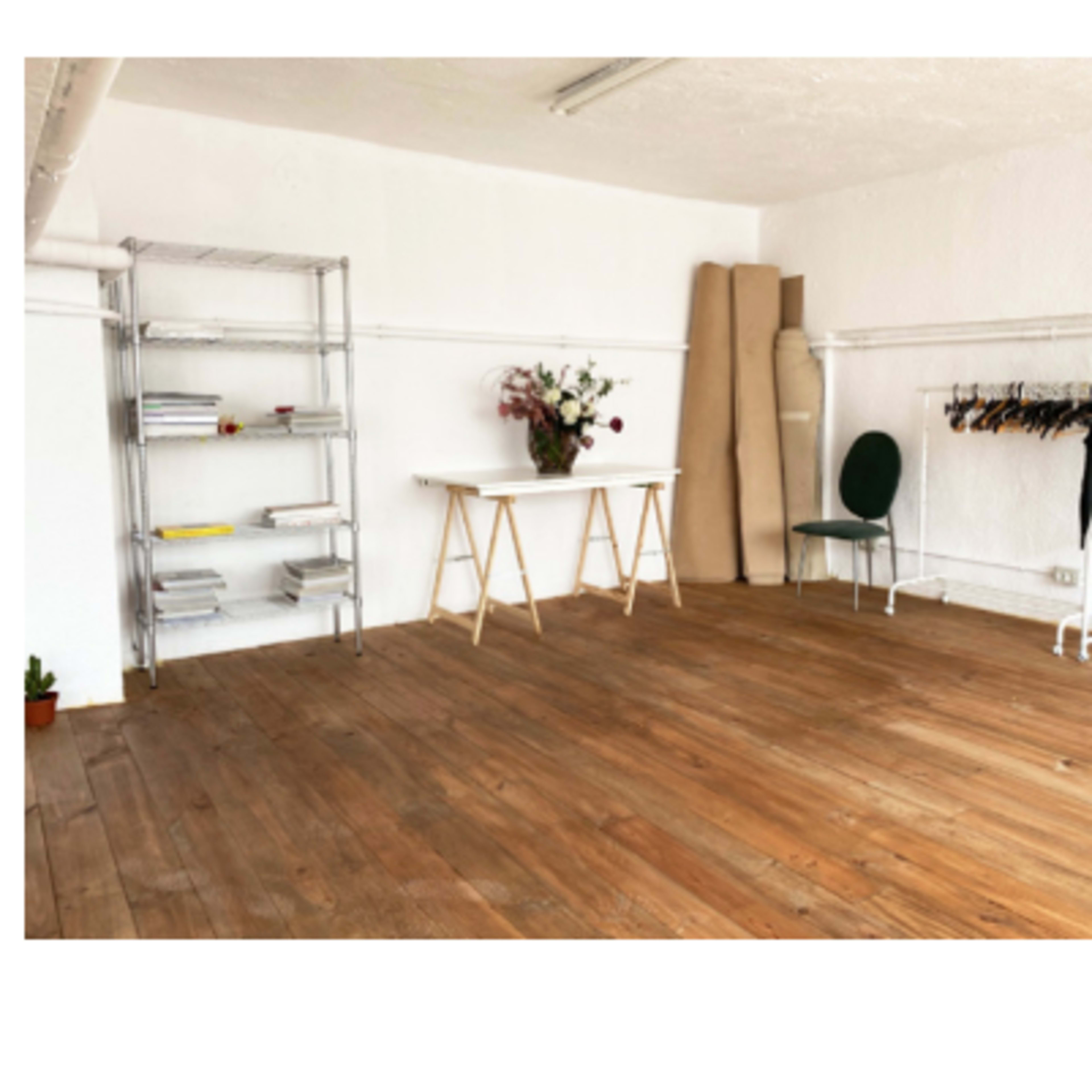 Two views of a spacious, wooden-floored room with large windows and minimalist decor.
