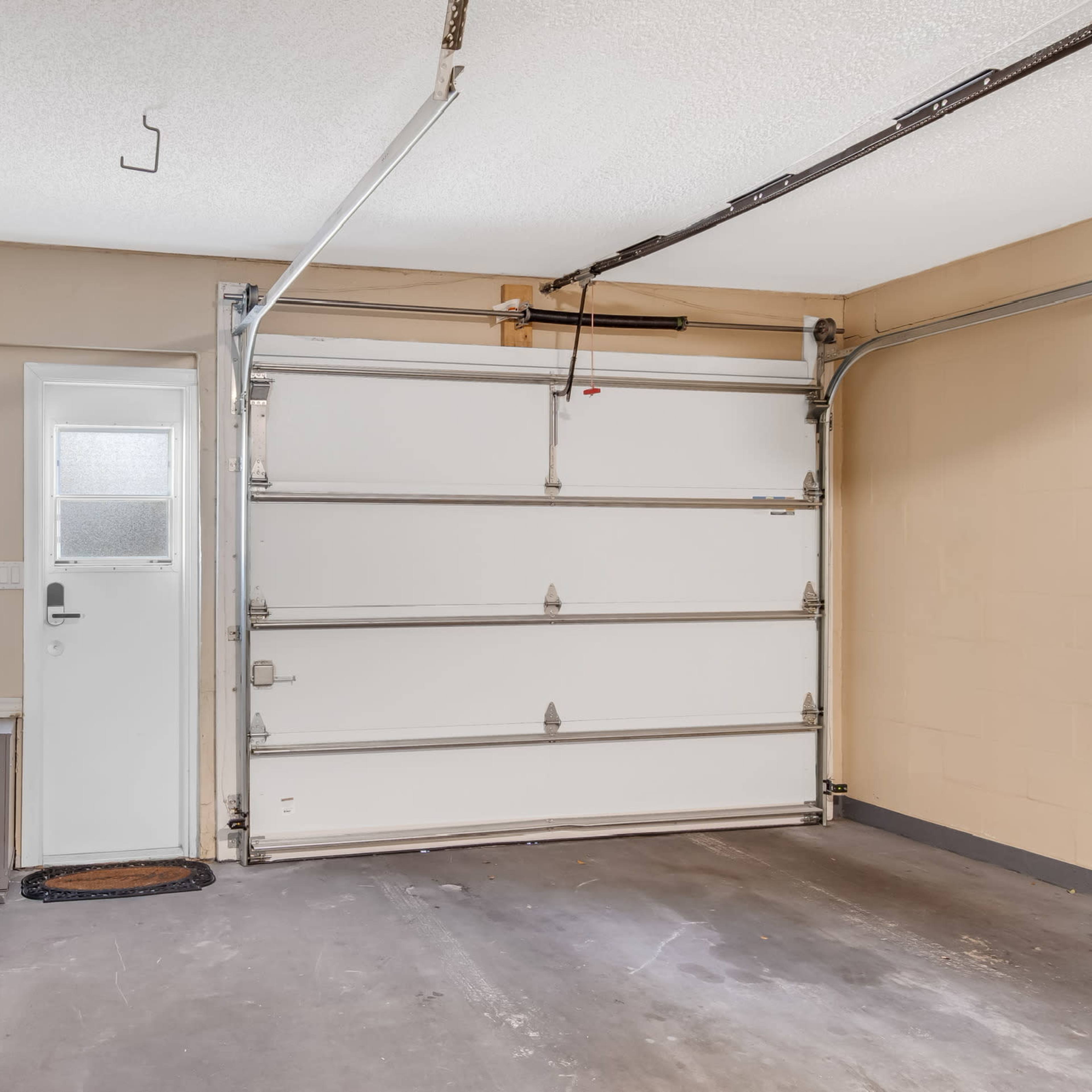A garage with a laundry area on the left, a door leading outside, and a large garage door on the right.