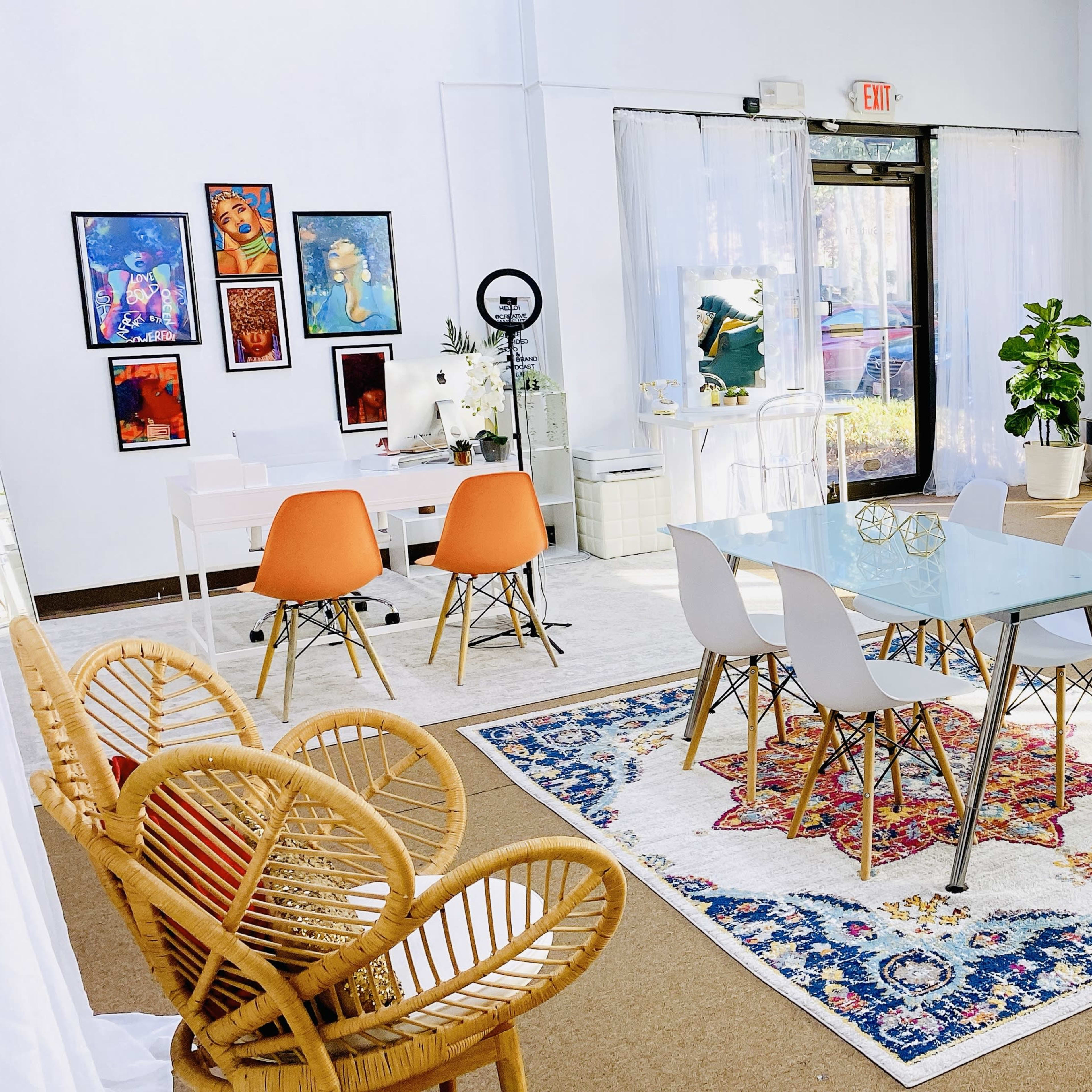 A bright, modern interior space featuring a glass dining table surrounded by white and orange chairs, complemented by a blue sofa and several potted plants.