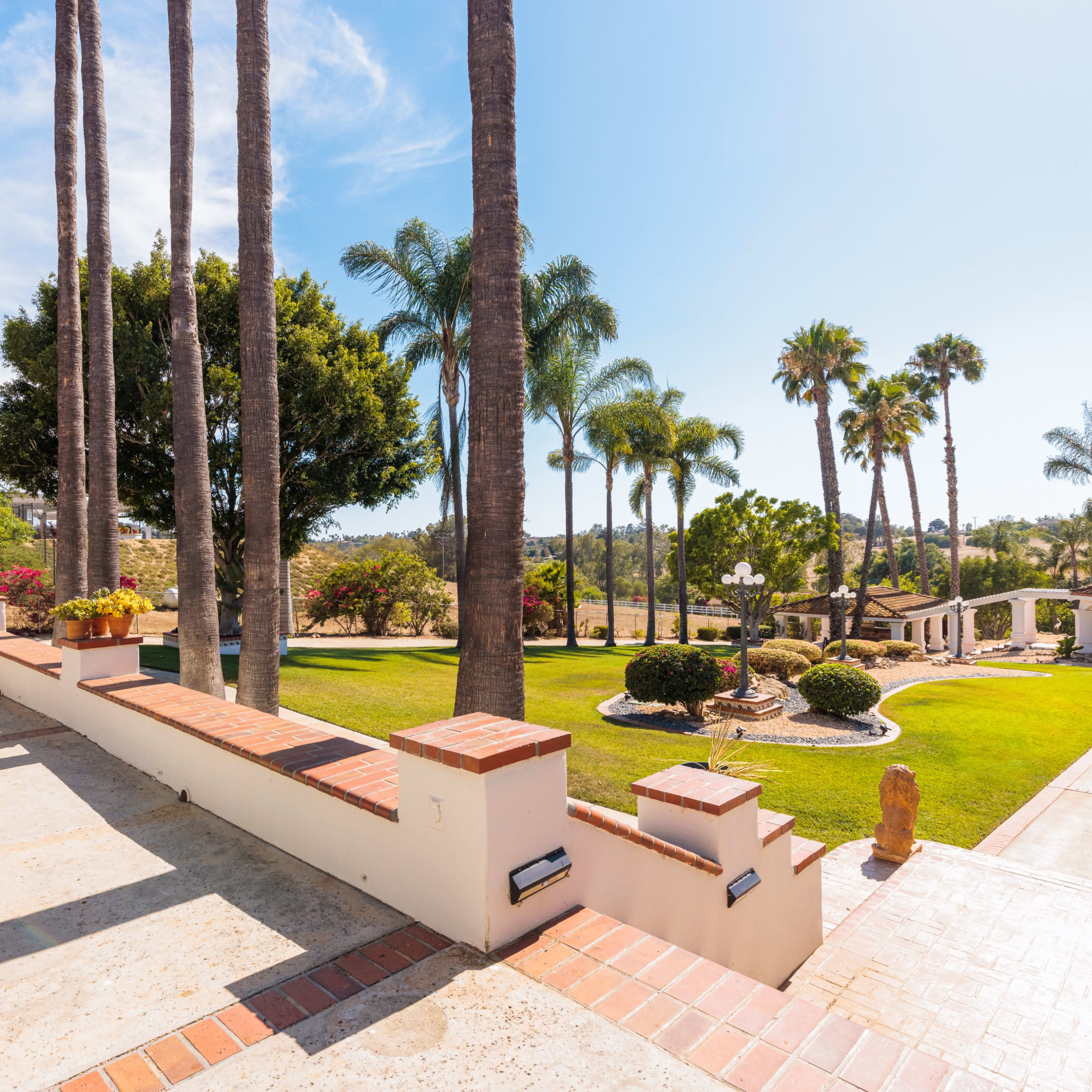 A landscaped outdoor area with palm trees, well-maintained grass, and a patio featuring outdoor furniture.