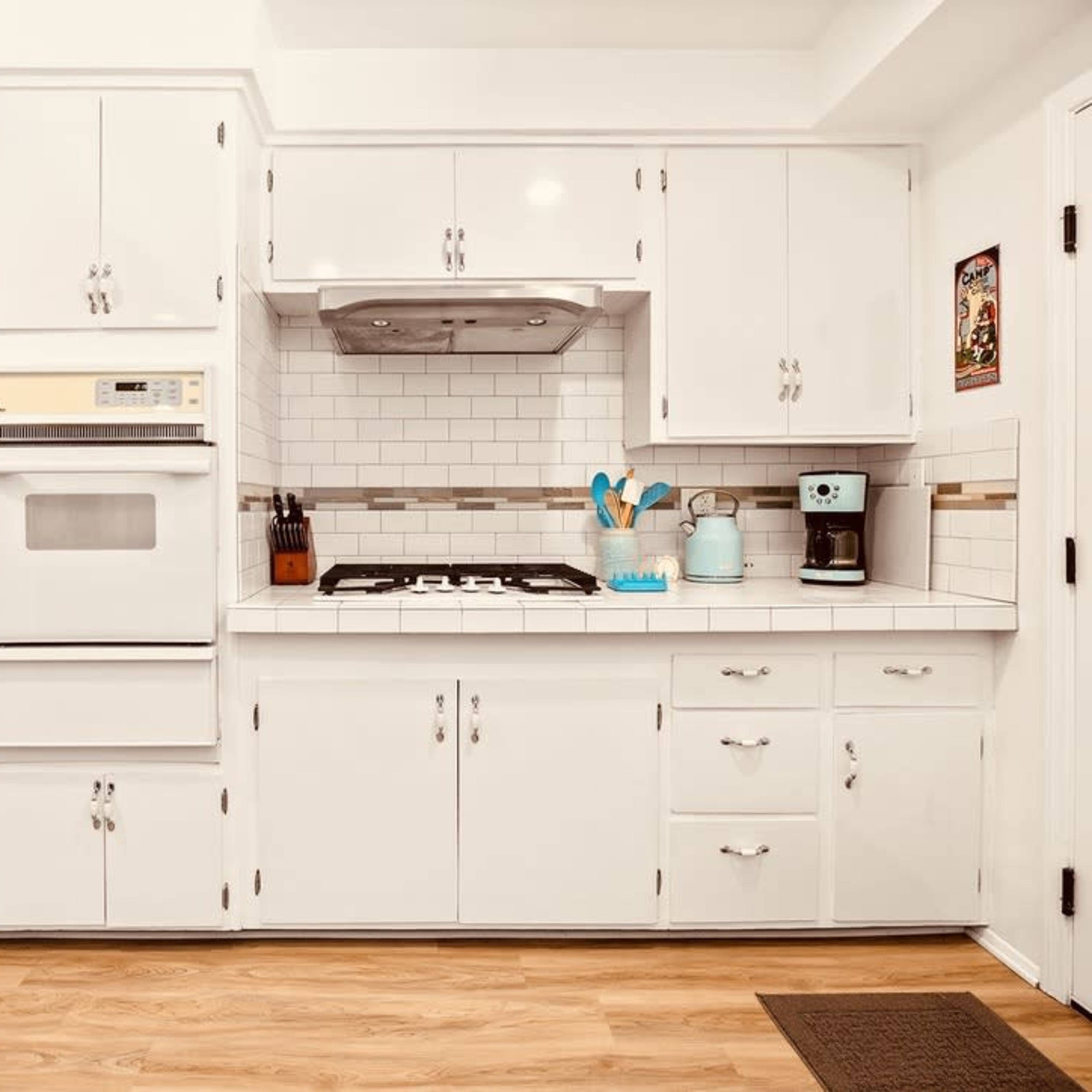 The kitchen features white cabinetry, stainless steel appliances, and a tiled backsplash with a stove and countertop arranged in a functional layout.