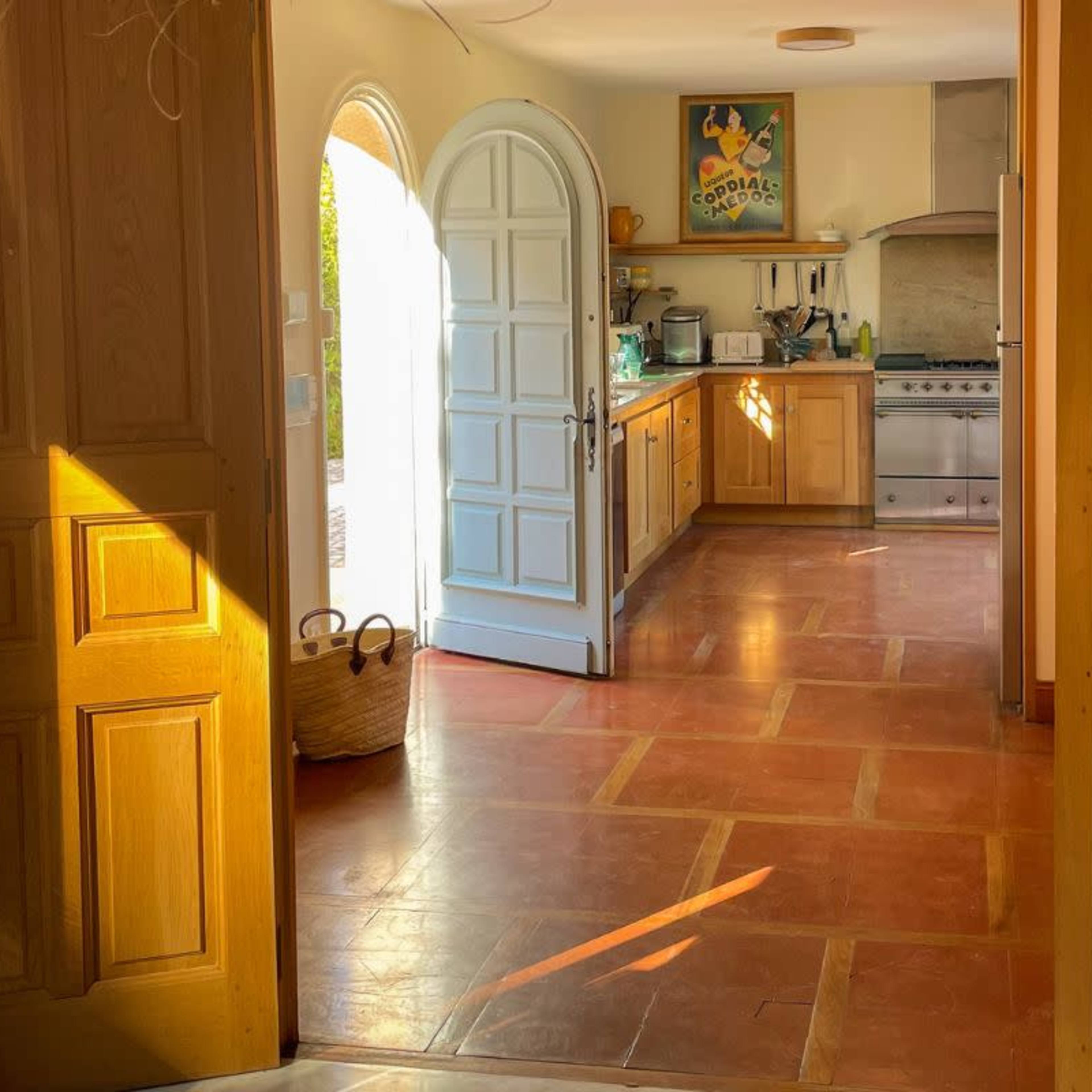 A view of a kitchen area featuring wooden cabinets, a stainless steel oven, and an arched doorway leading to another room.
