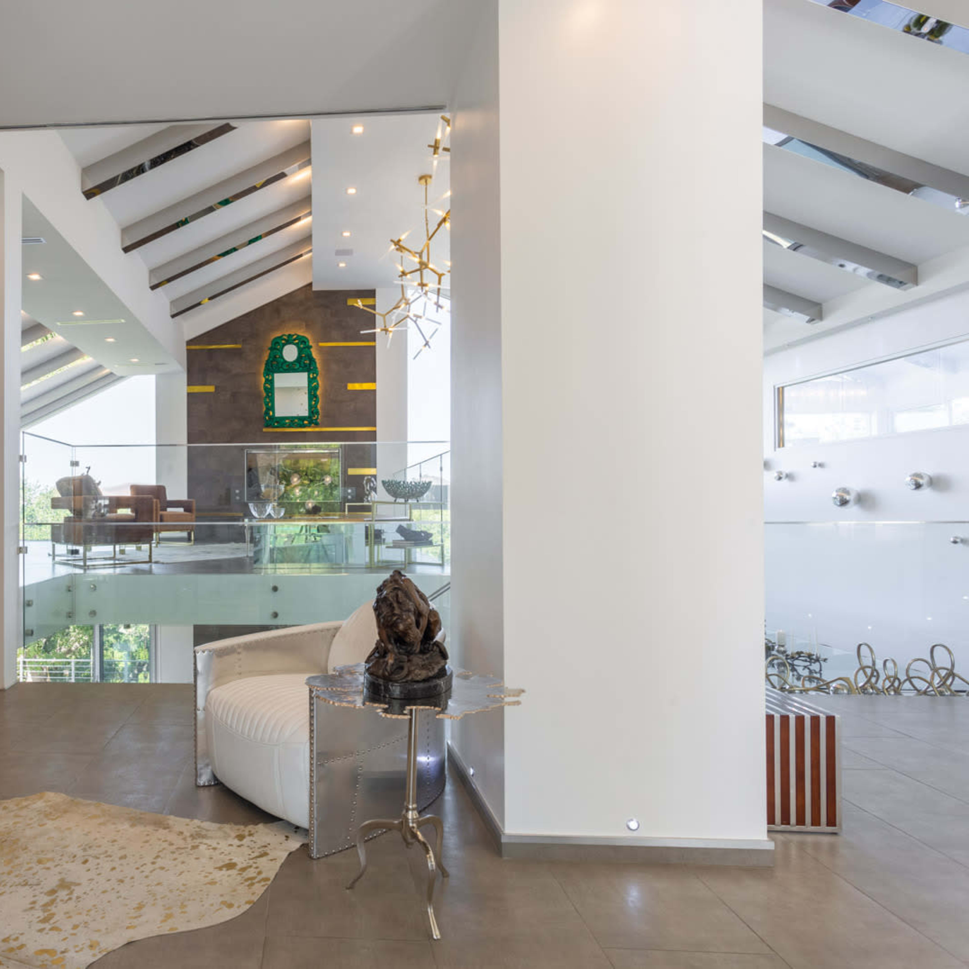 A modern interior space featuring a grand piano, a white armchair, and large windows that allow natural light to illuminate the area.