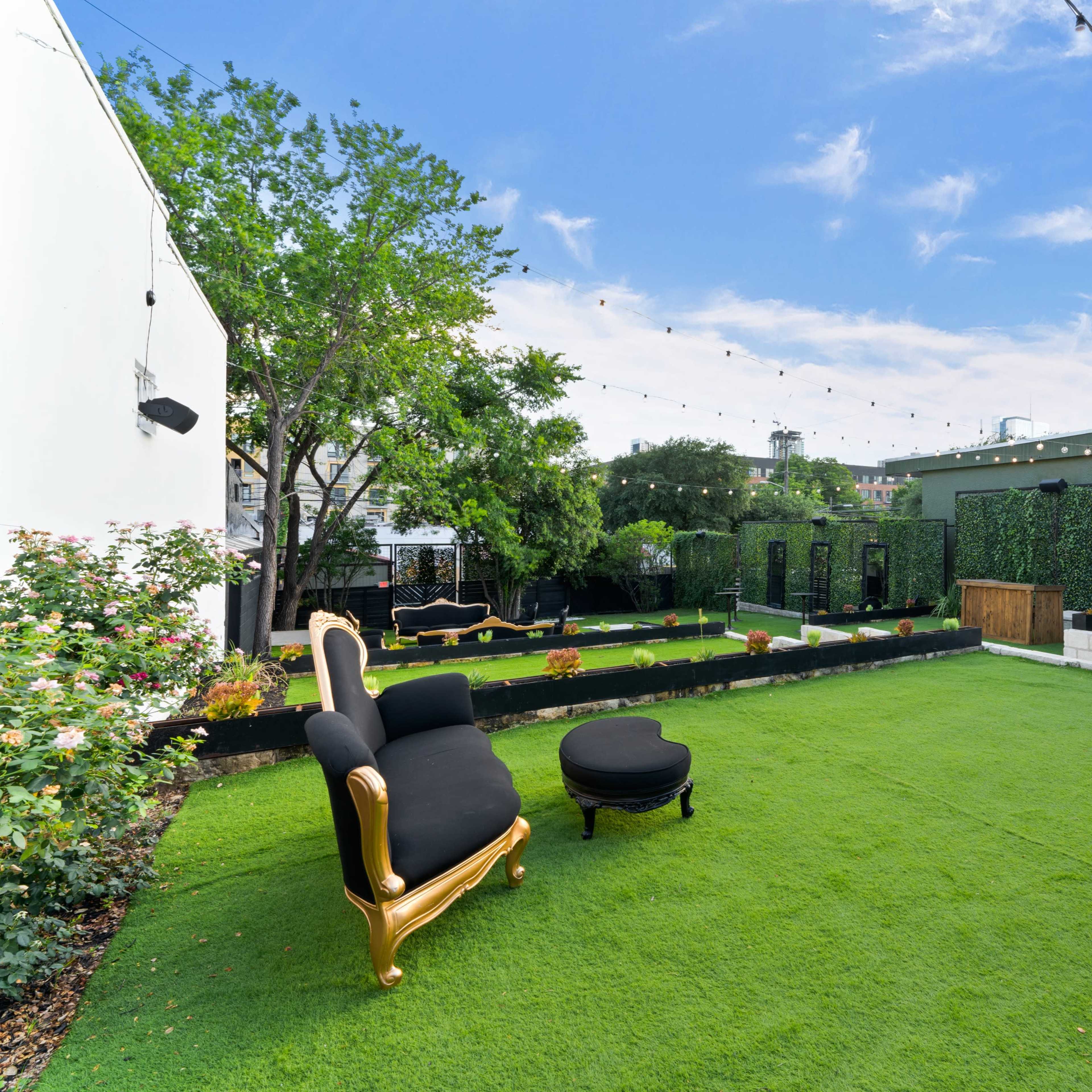 A landscaped rooftop area featuring green artificial turf, decorative seating, and string lights overhead.