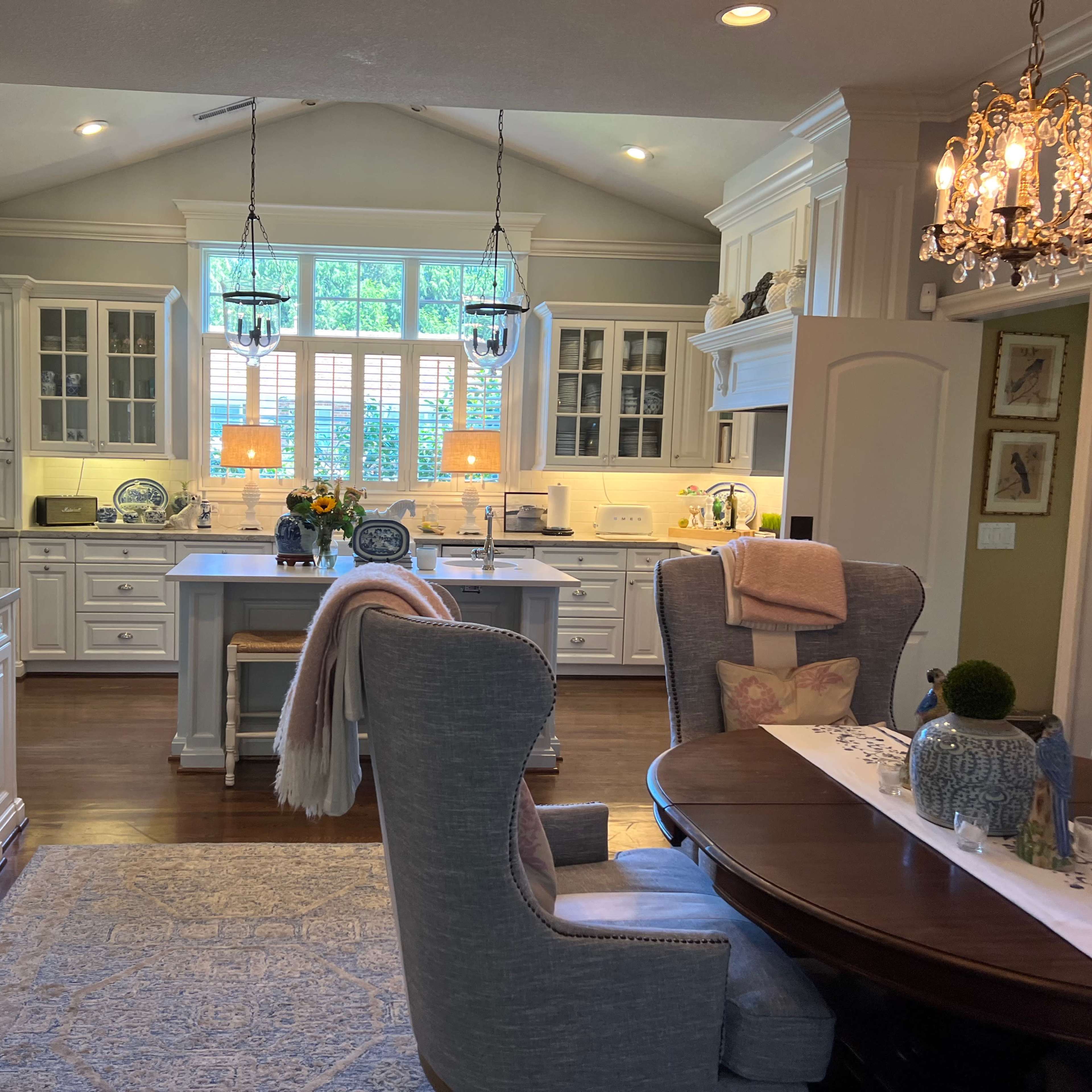 A spacious kitchen and dining area featuring white cabinets, a large island, and a round dining table with upholstered chairs.
