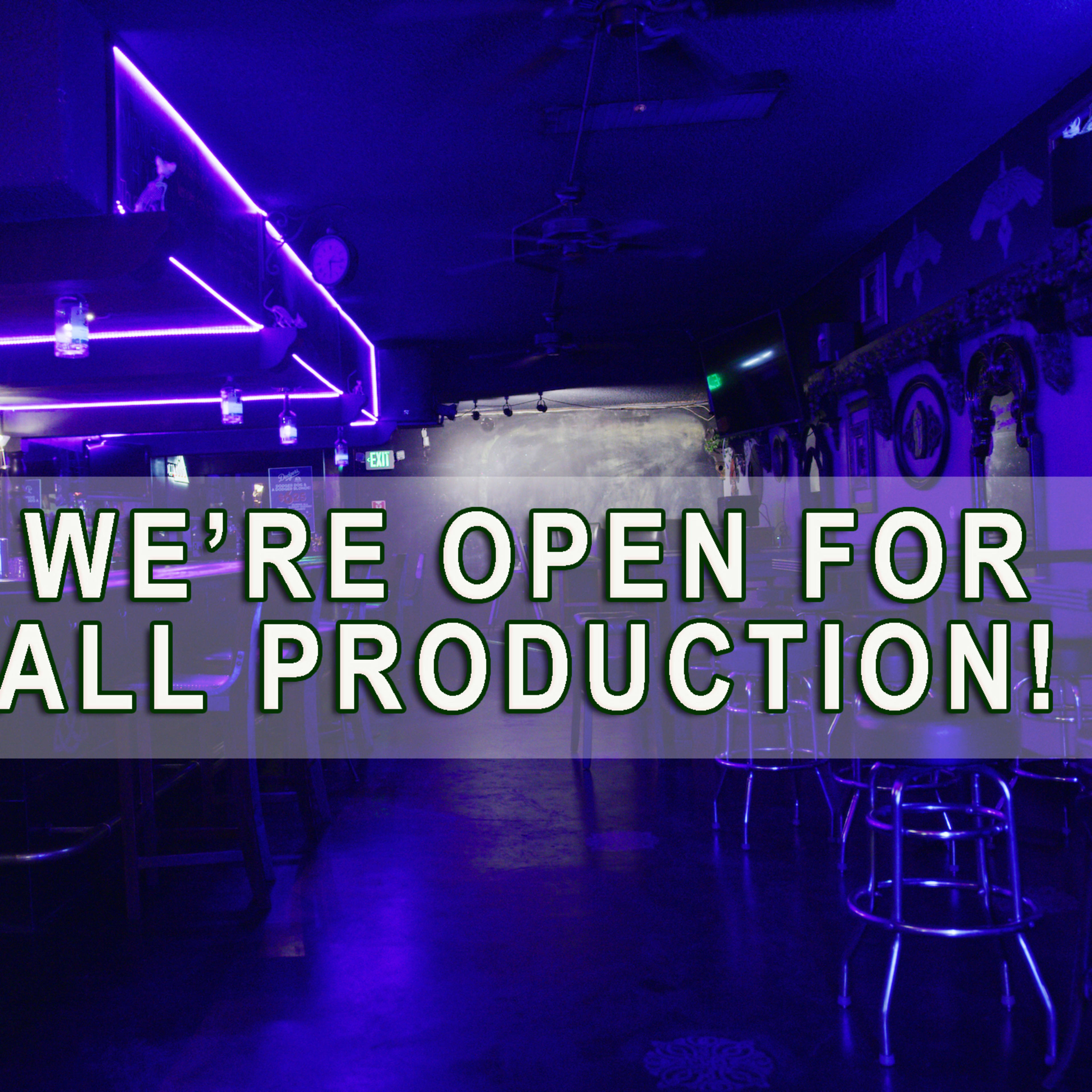 A dimly lit bar with purple neon lighting and a sign that states, "WE'RE OPEN FOR ALL PRODUCTION!"