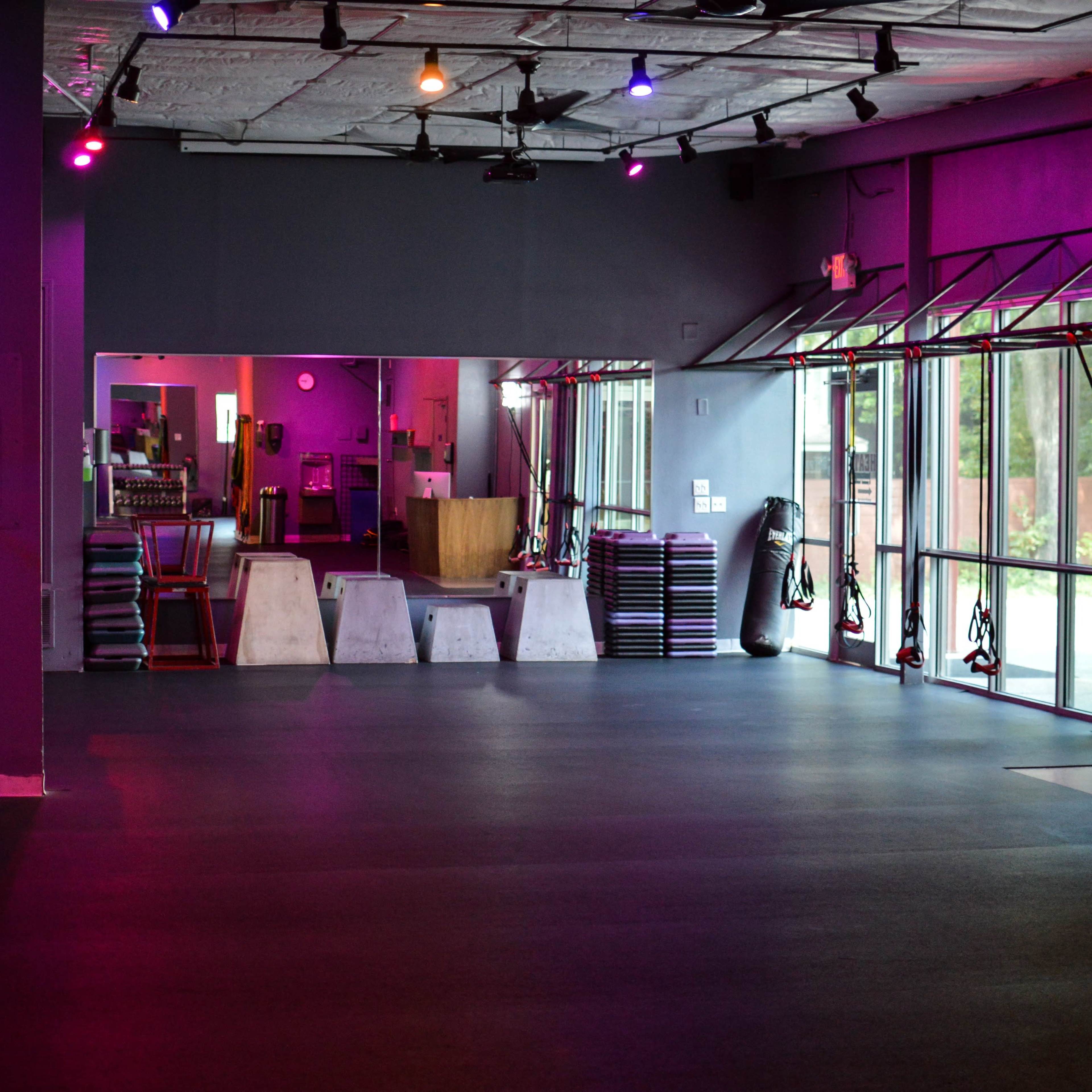 An interior view of a gym with visible exercise equipment and dim lighting.