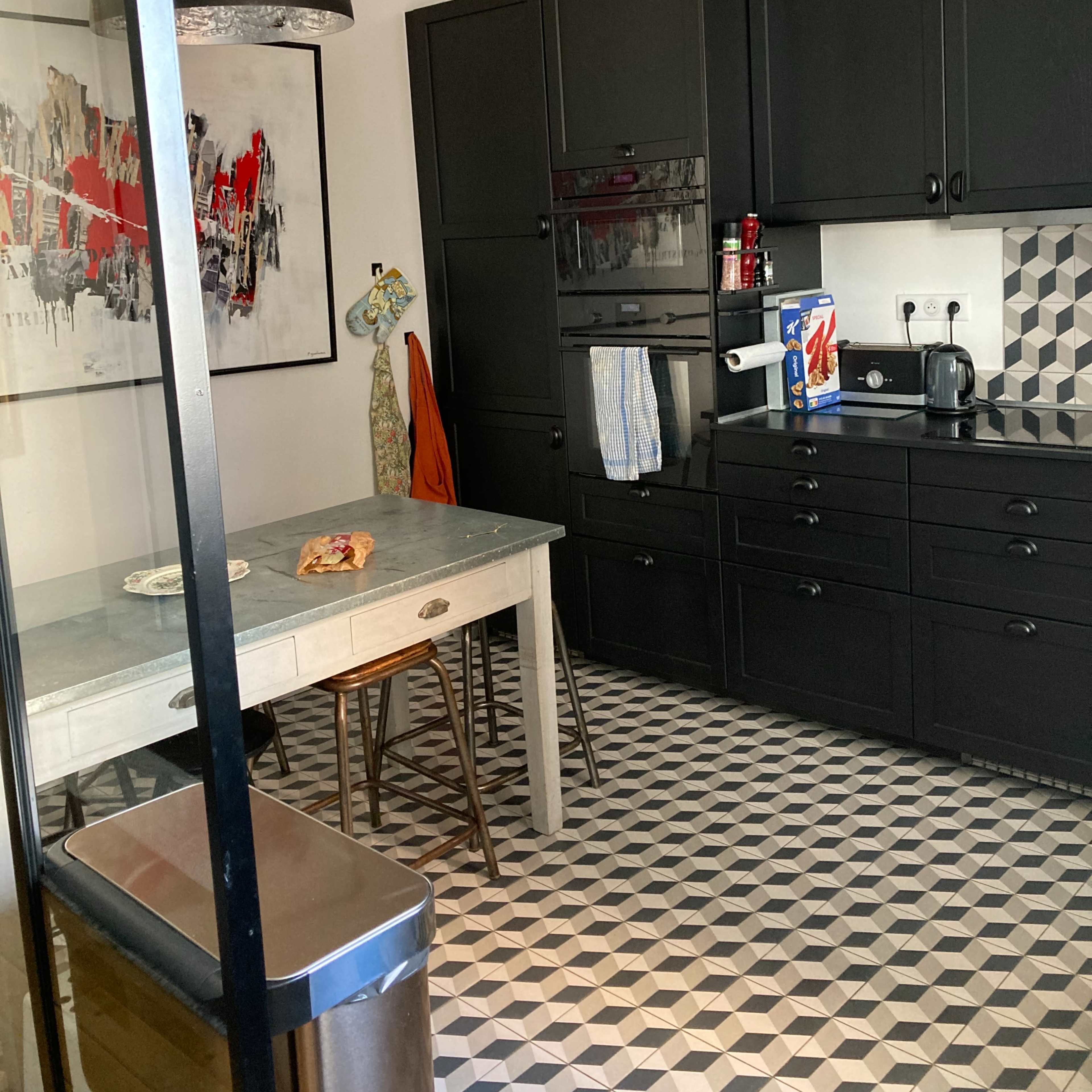 A black and white tiled kitchen with modern cabinets, a wooden dining table, and various kitchen appliances.