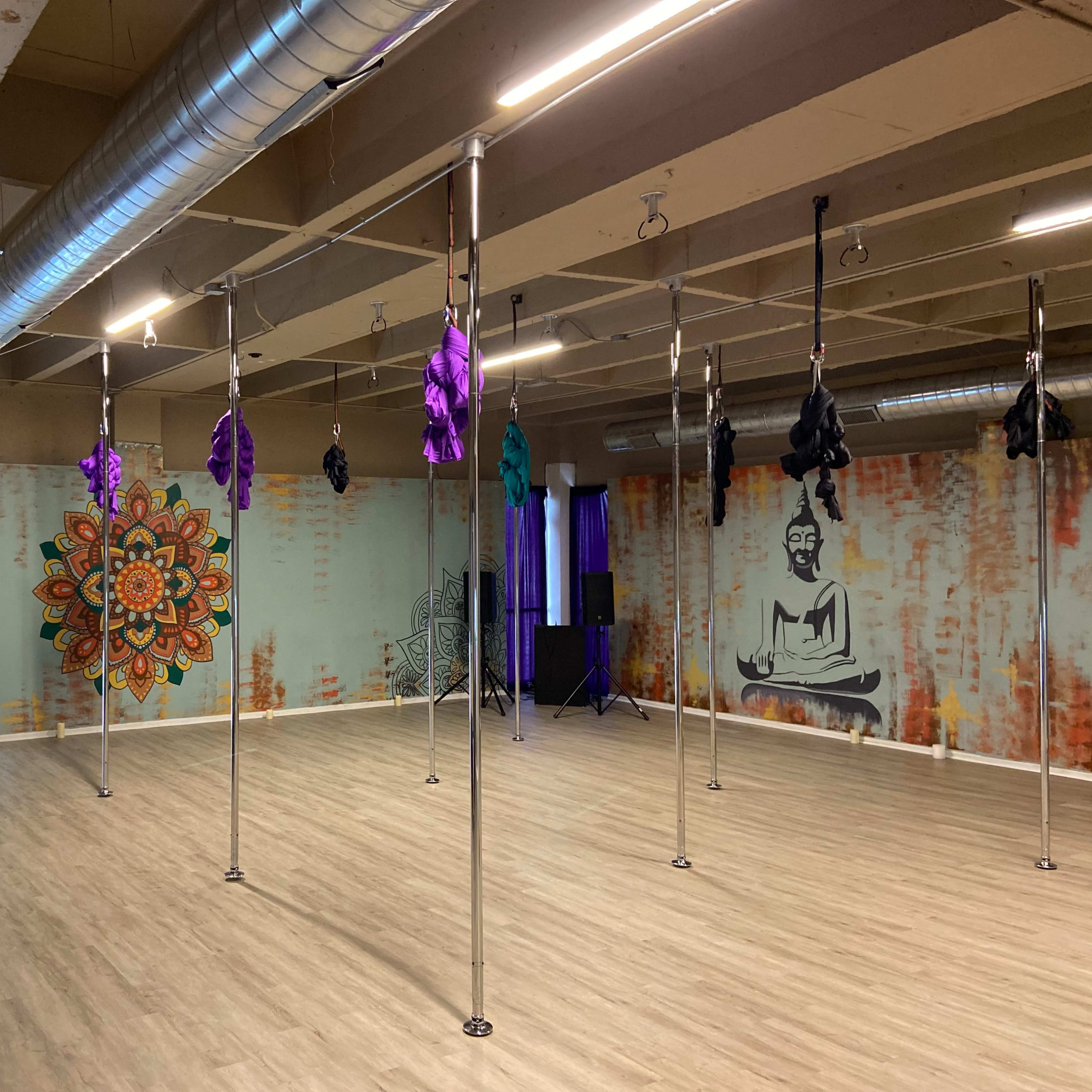 A brightly lit room with multiple vertical poles, decorated walls featuring a mandala and a buddha image, and a sign that says "herbo culture."