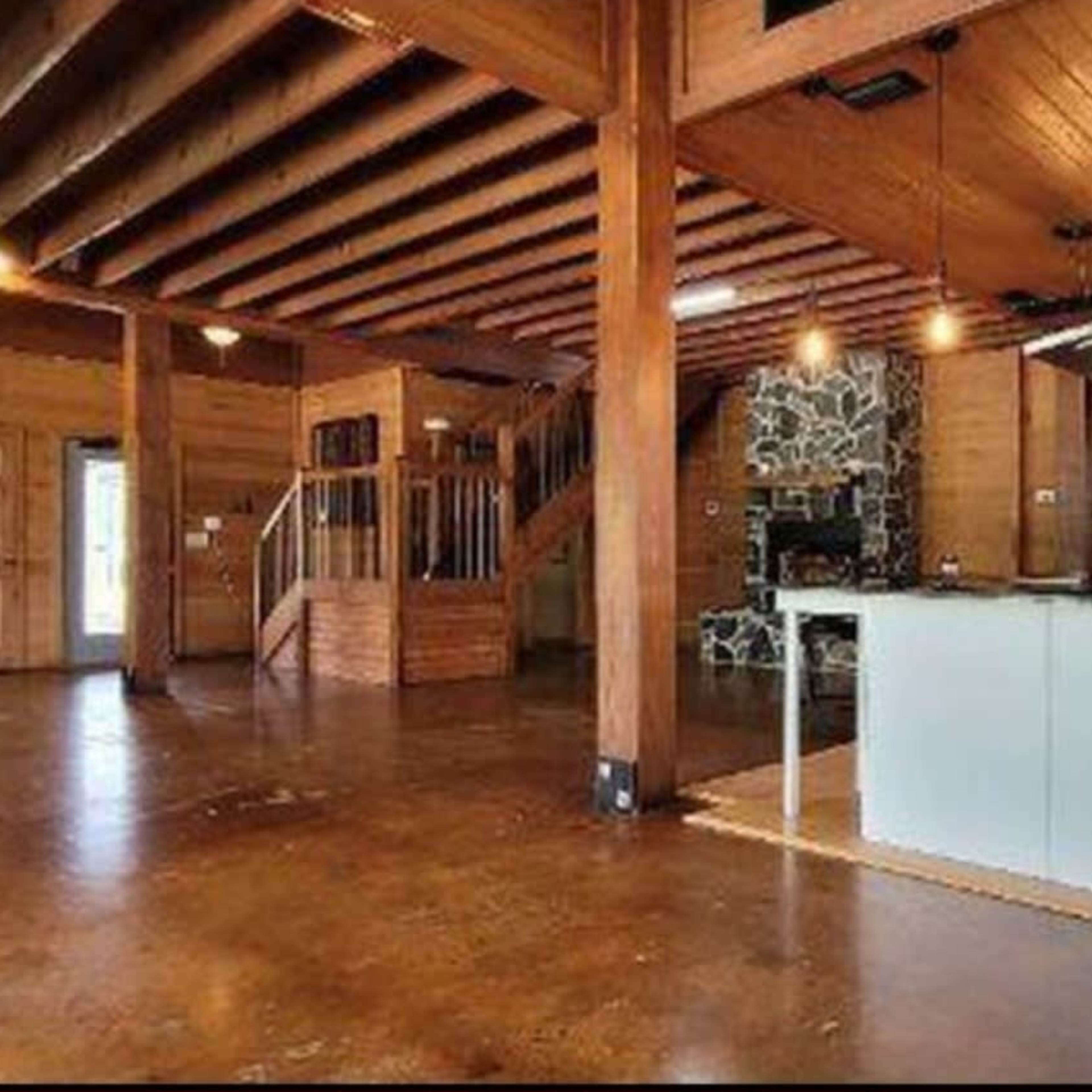 The spacious interior features wooden beams, a stone fireplace, and a modern kitchen with an island.