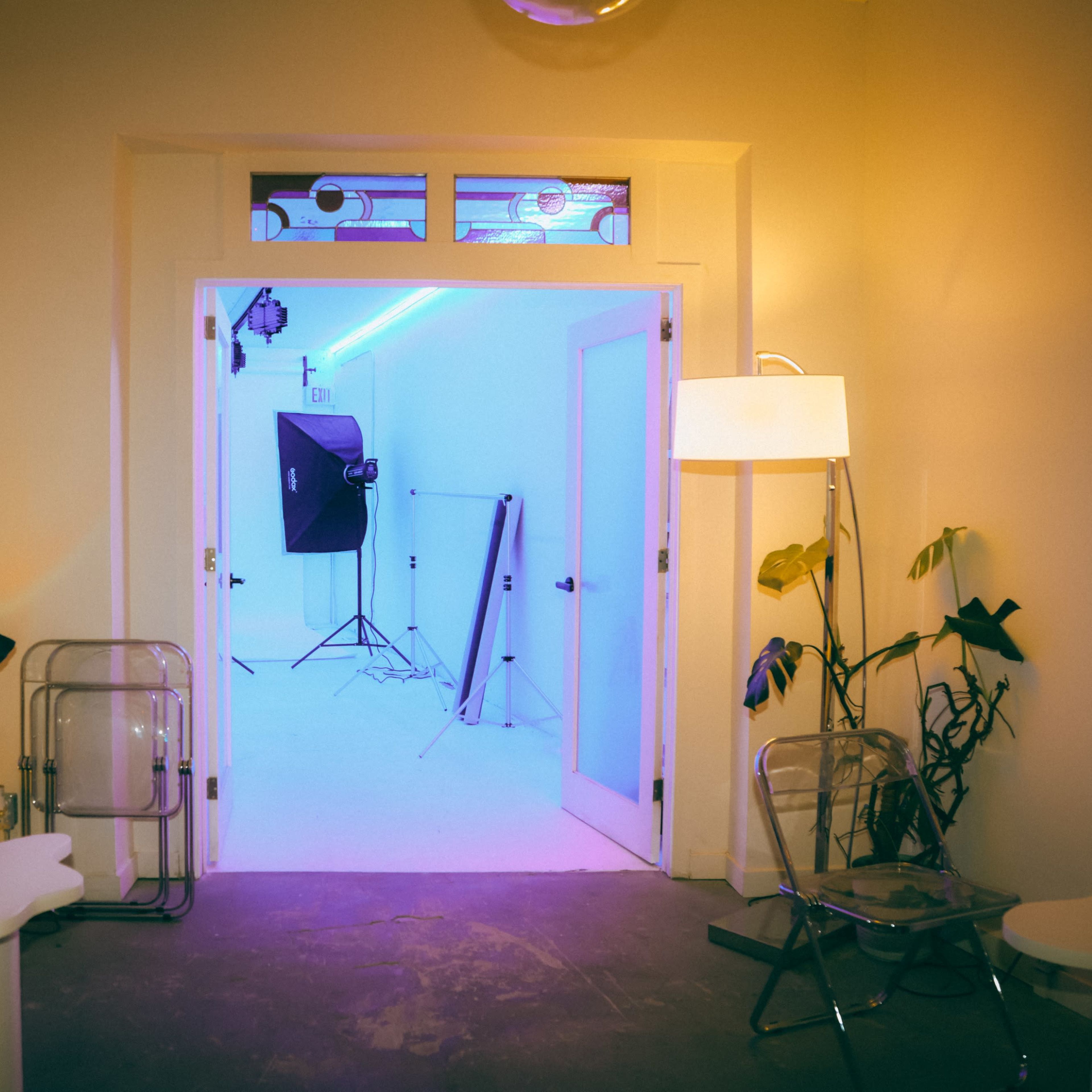 A well-lit studio space is visible through an open door, featuring a white backdrop, photography equipment, and minimalist furniture.