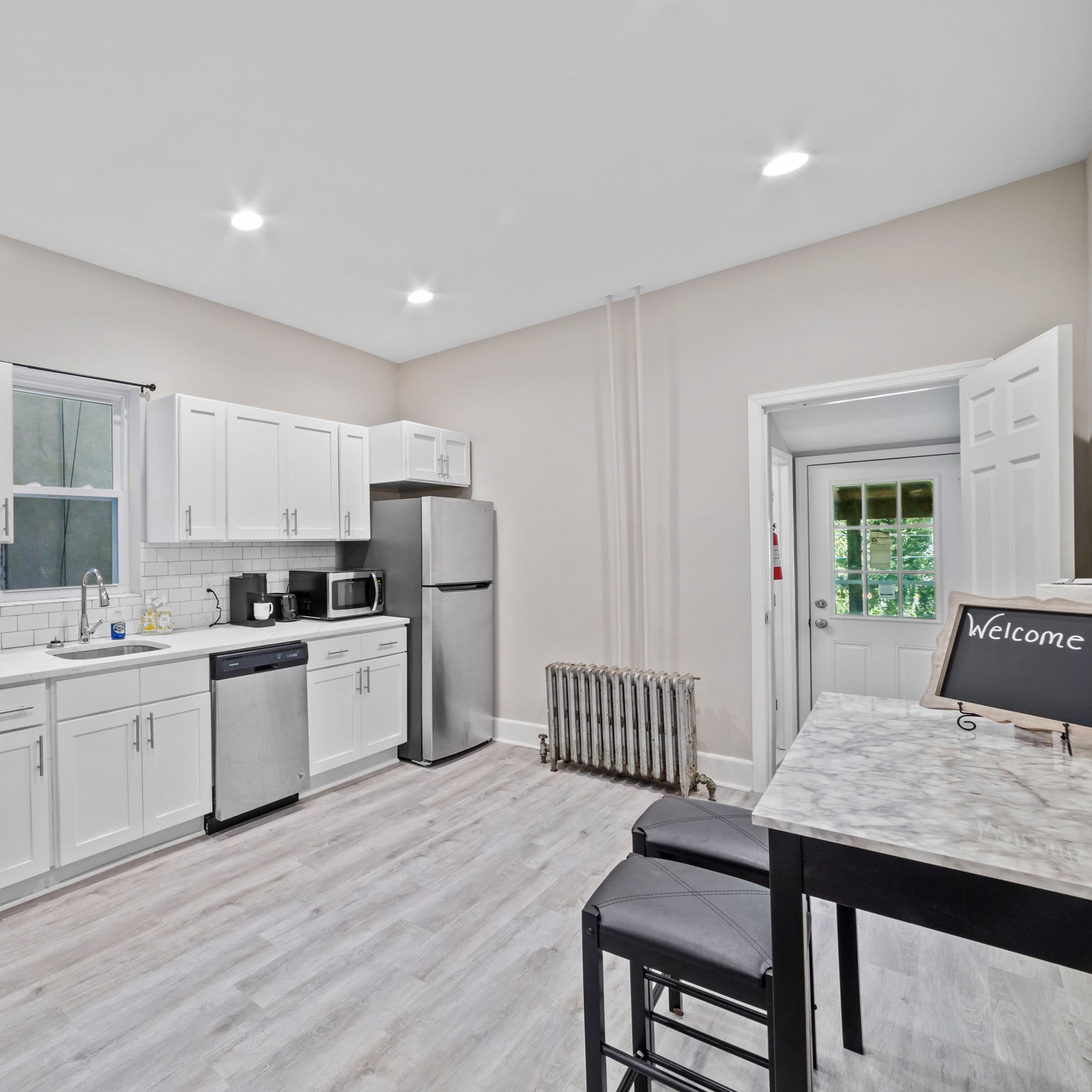 A modern kitchen with white cabinets, stainless steel appliances, and a small dining area with a table and chairs.