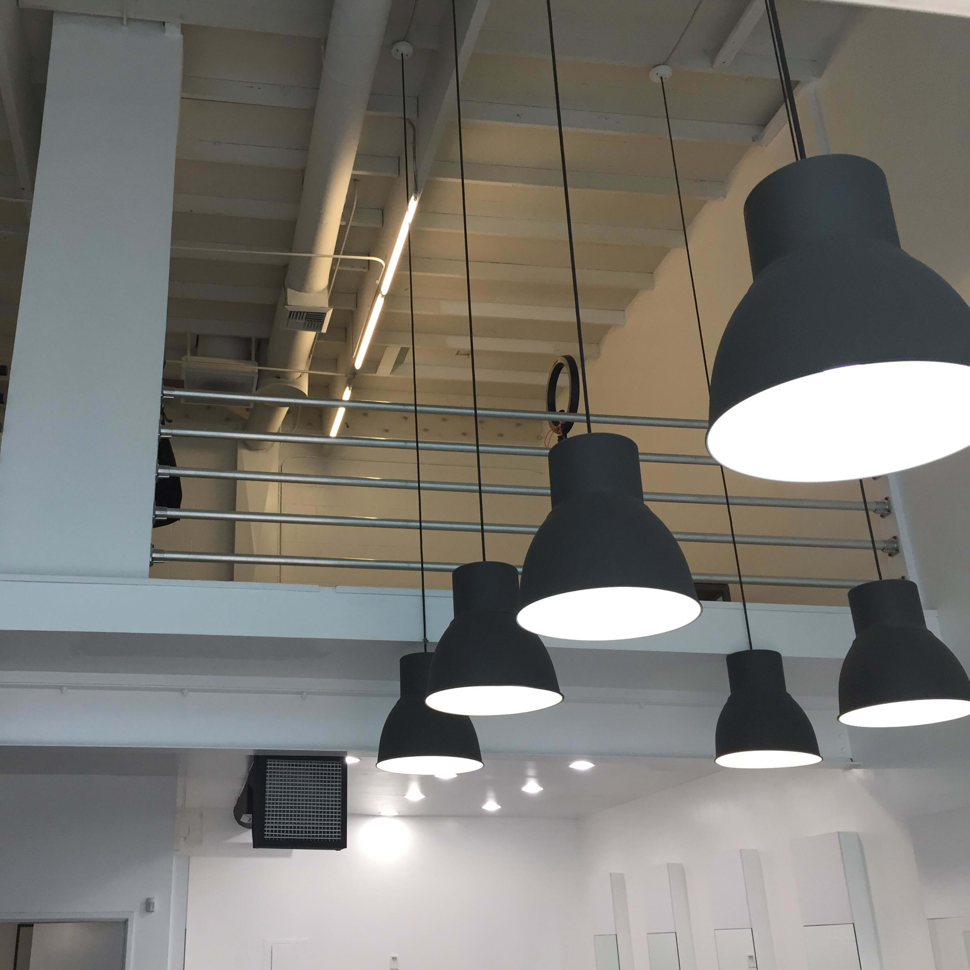 A modern interior with a staircase leading to a second level, featuring large hanging light fixtures and a minimalistic design.