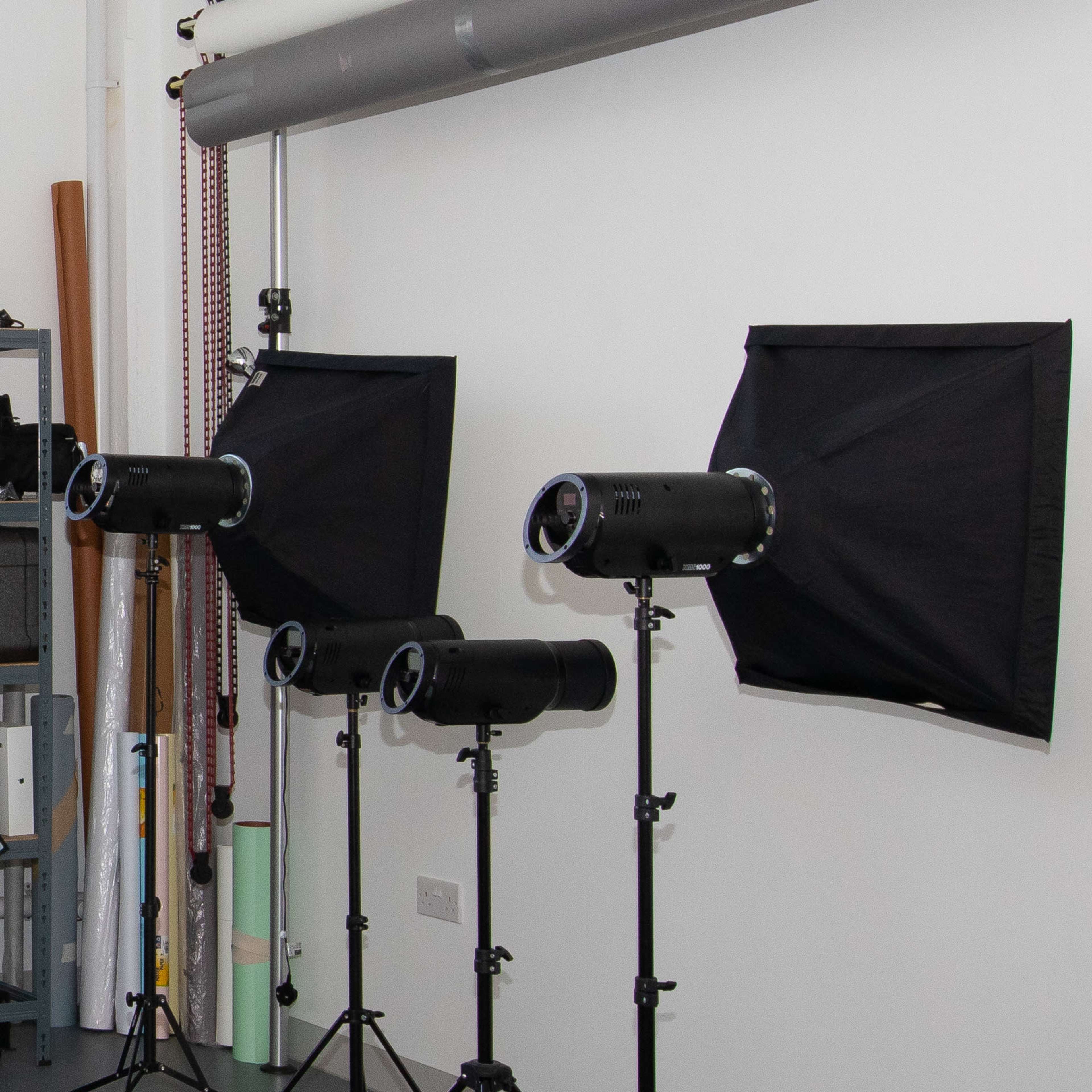 Three lighting setups with softboxes and a wall clock in a photography studio.