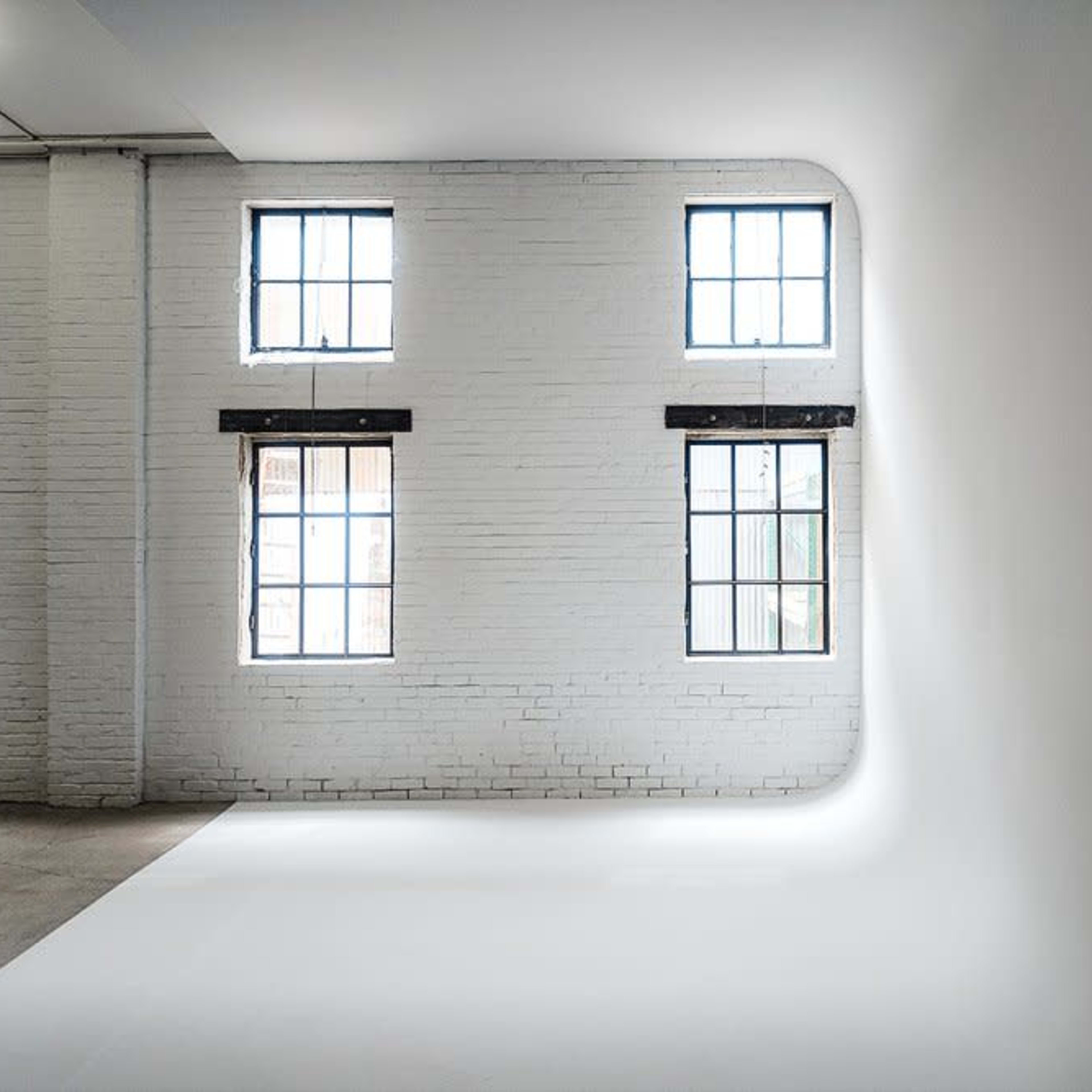 A minimalist interior space with white walls and large windows illuminating the room.