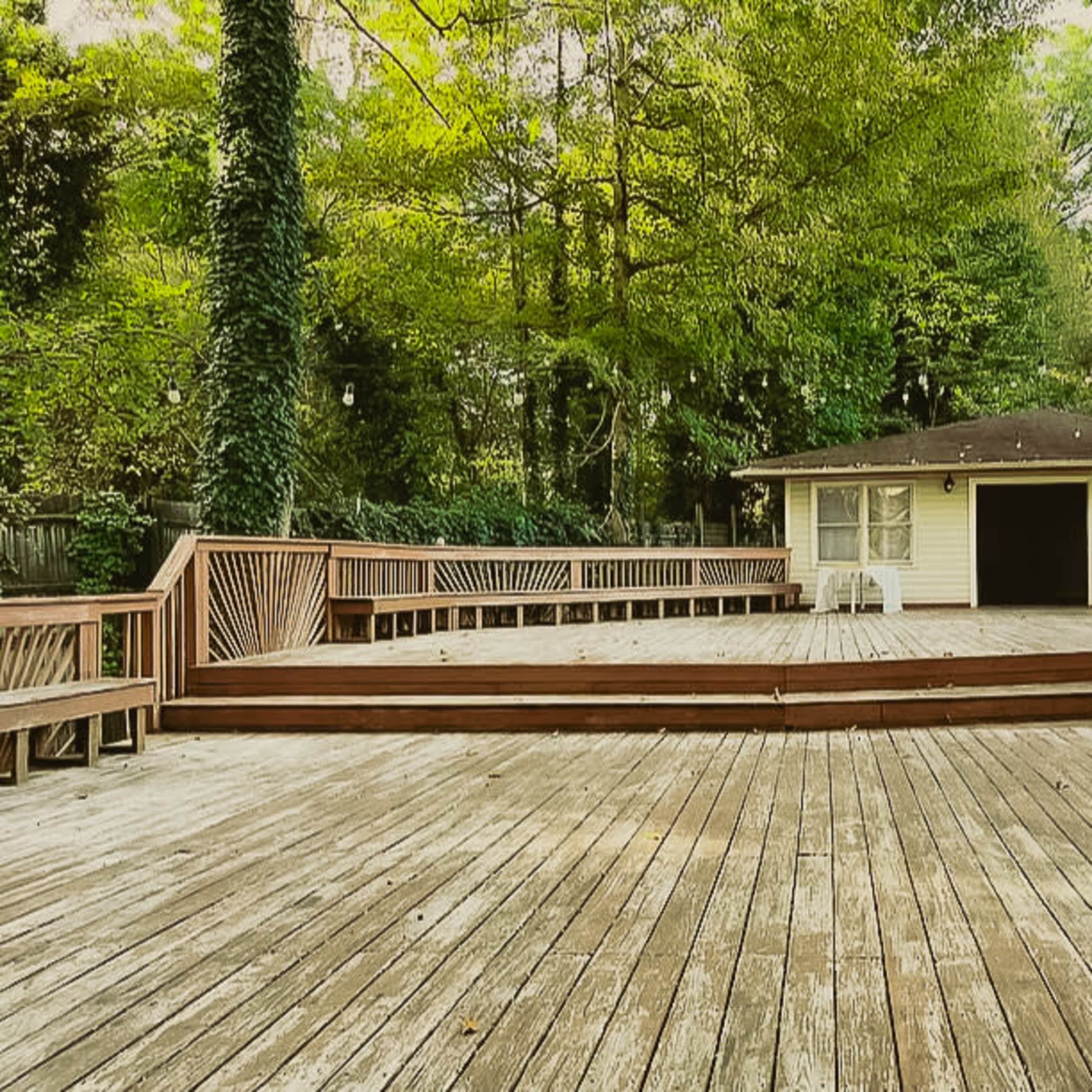 An expansive wooden deck in a wooded area, adjacent to a light-colored shed.