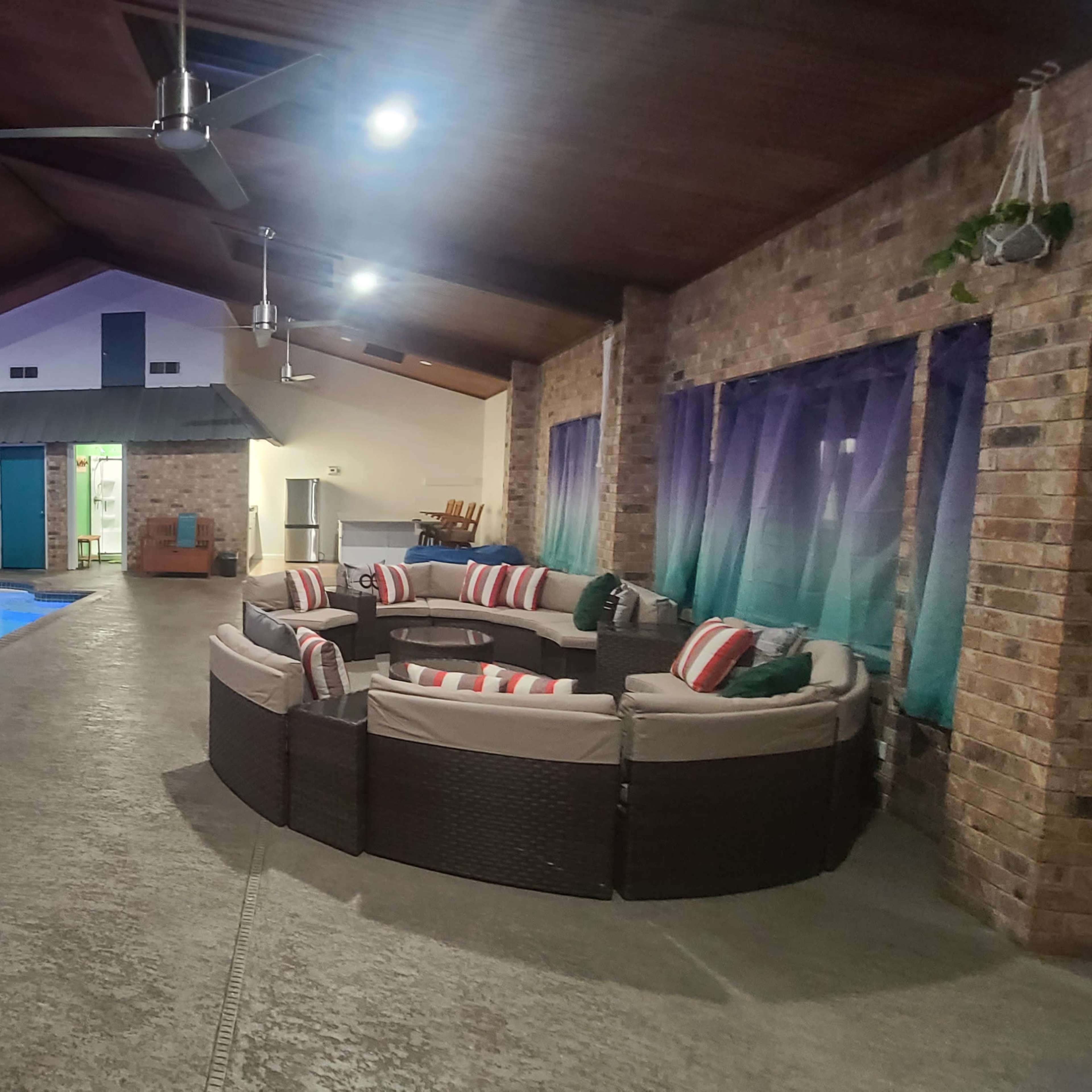 An indoor pool area with a circular seating arrangement and large windows partially covered by curtains.