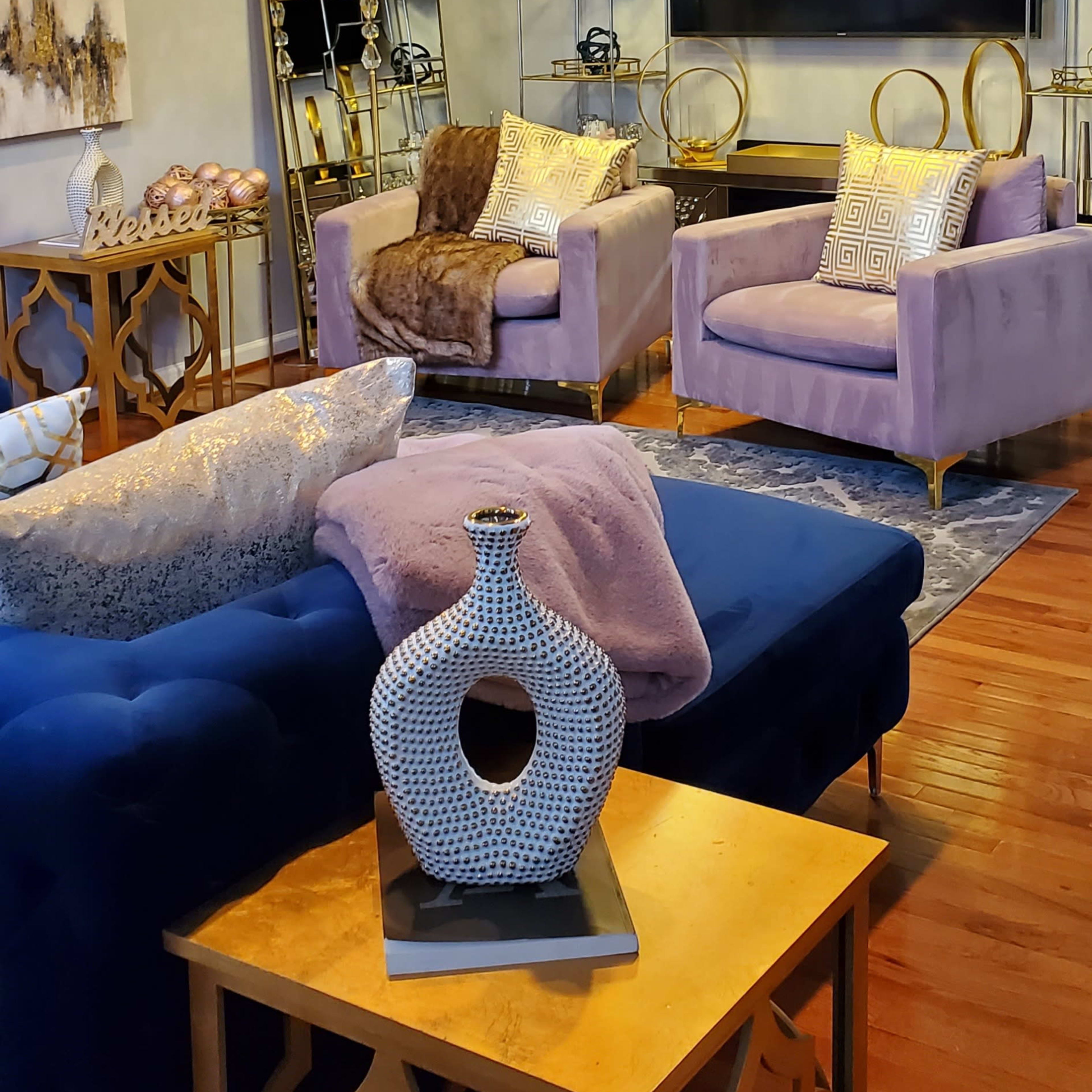 The living room features two purple chairs, a blue sofa, a large mirror, and a mounted television against a light blue wall.