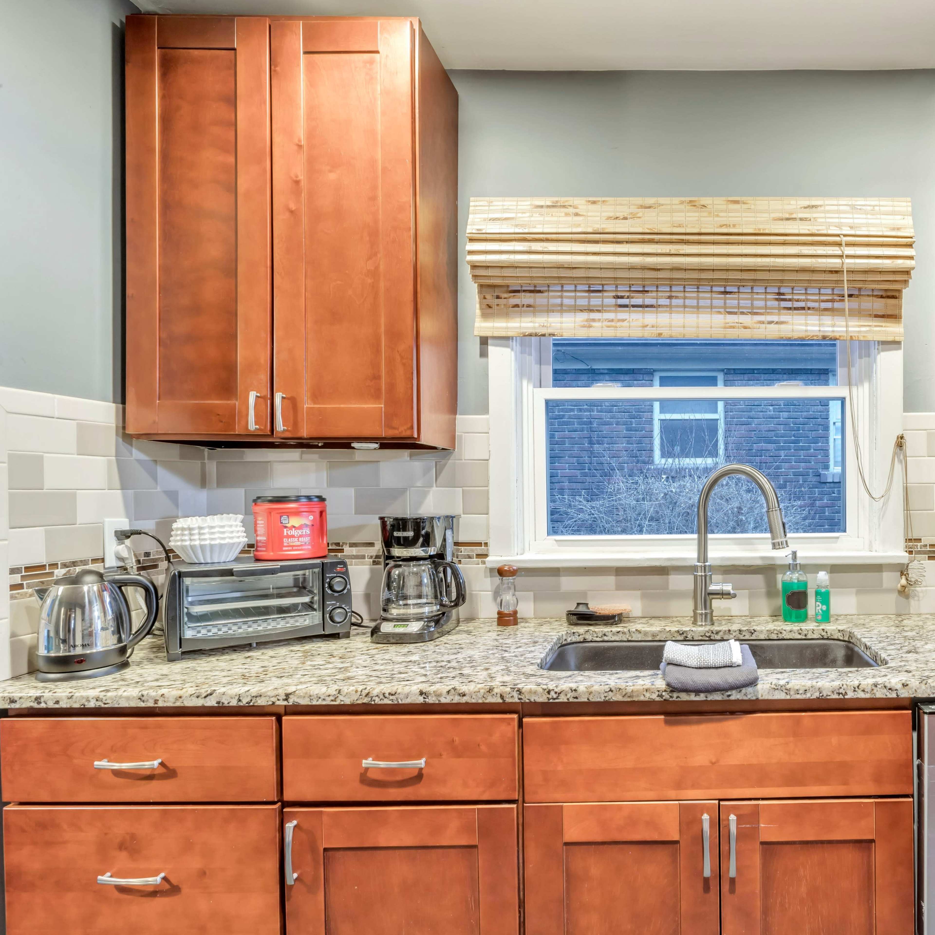 A modern kitchen features wooden cabinets, a stainless steel sink, and various appliances arranged neatly on the countertop.