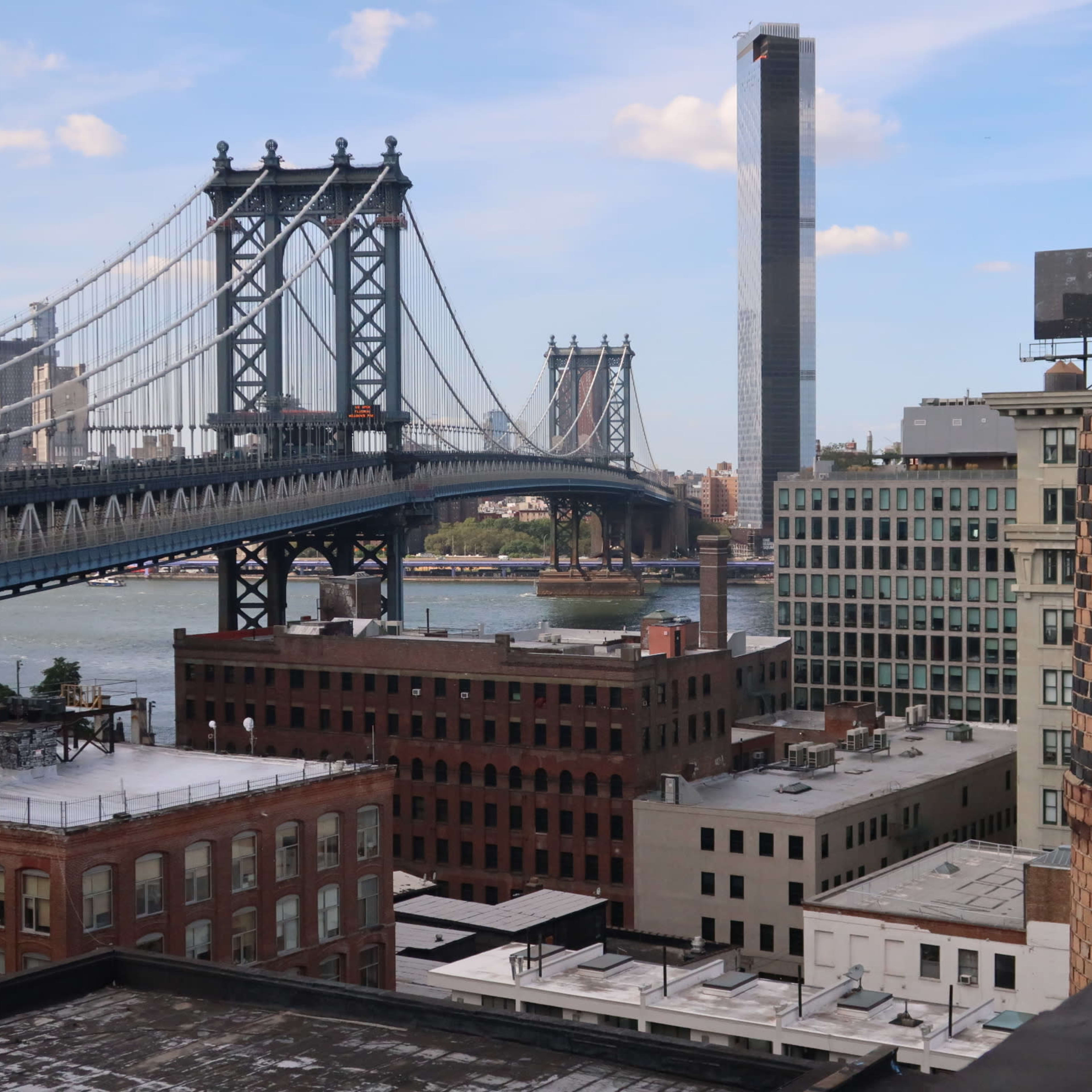 The Manhattan Bridge connecting two urban landscapes with buildings and the East River in the background.