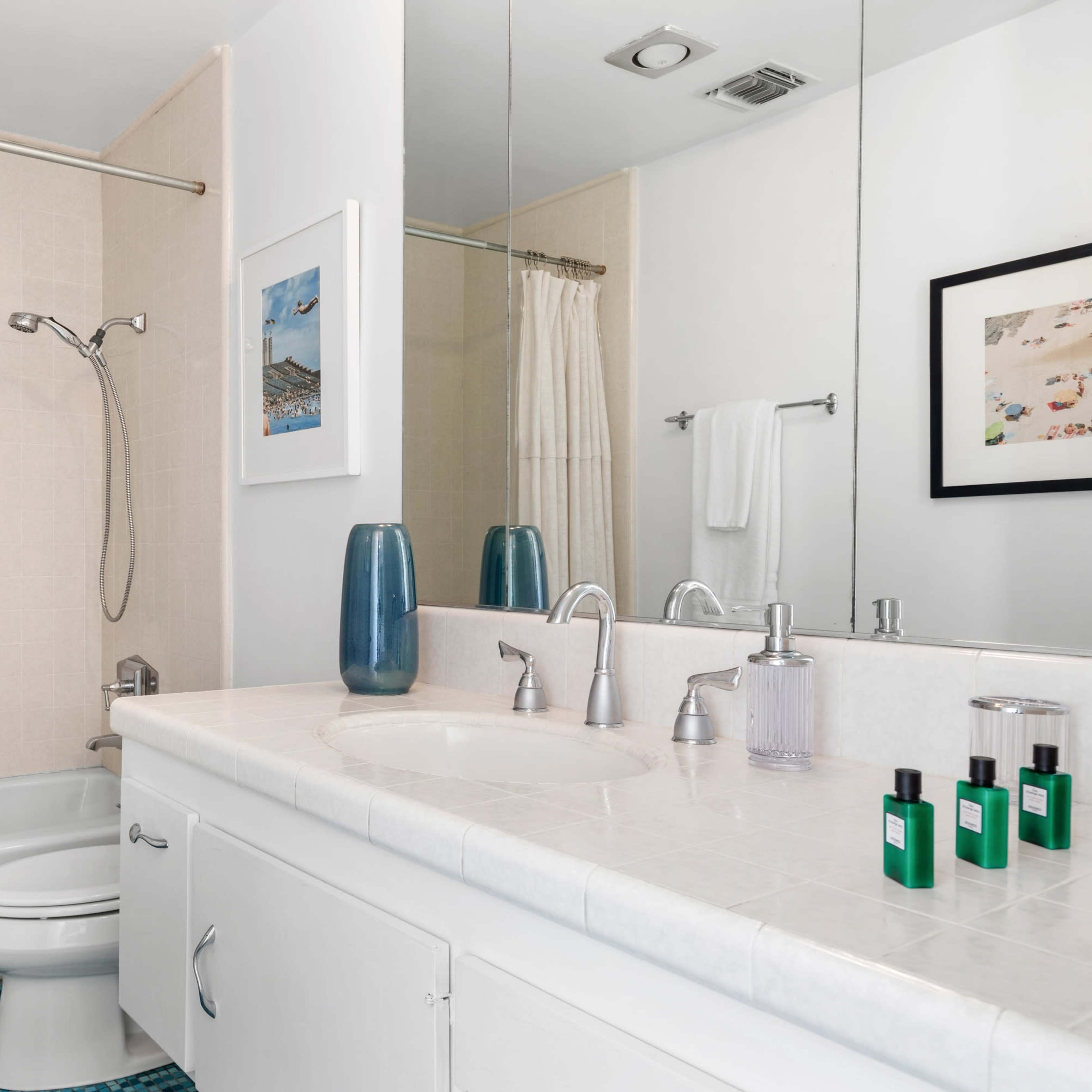 A modern bathroom featuring a bathtub, shower, double sink, and a large mirror above the sink area.
