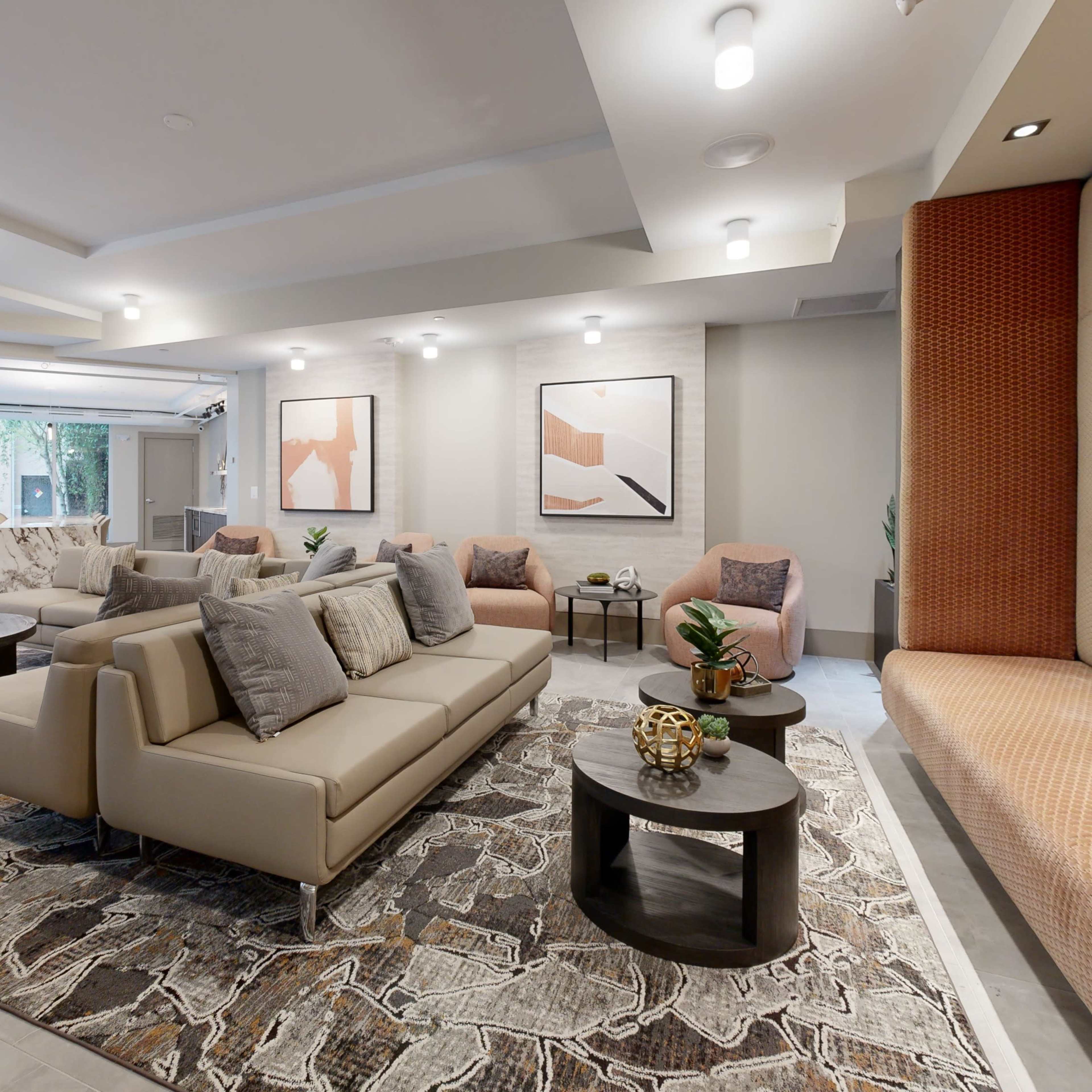 A modern lounge area with beige sofas, round tables, and decorative artwork on the walls.