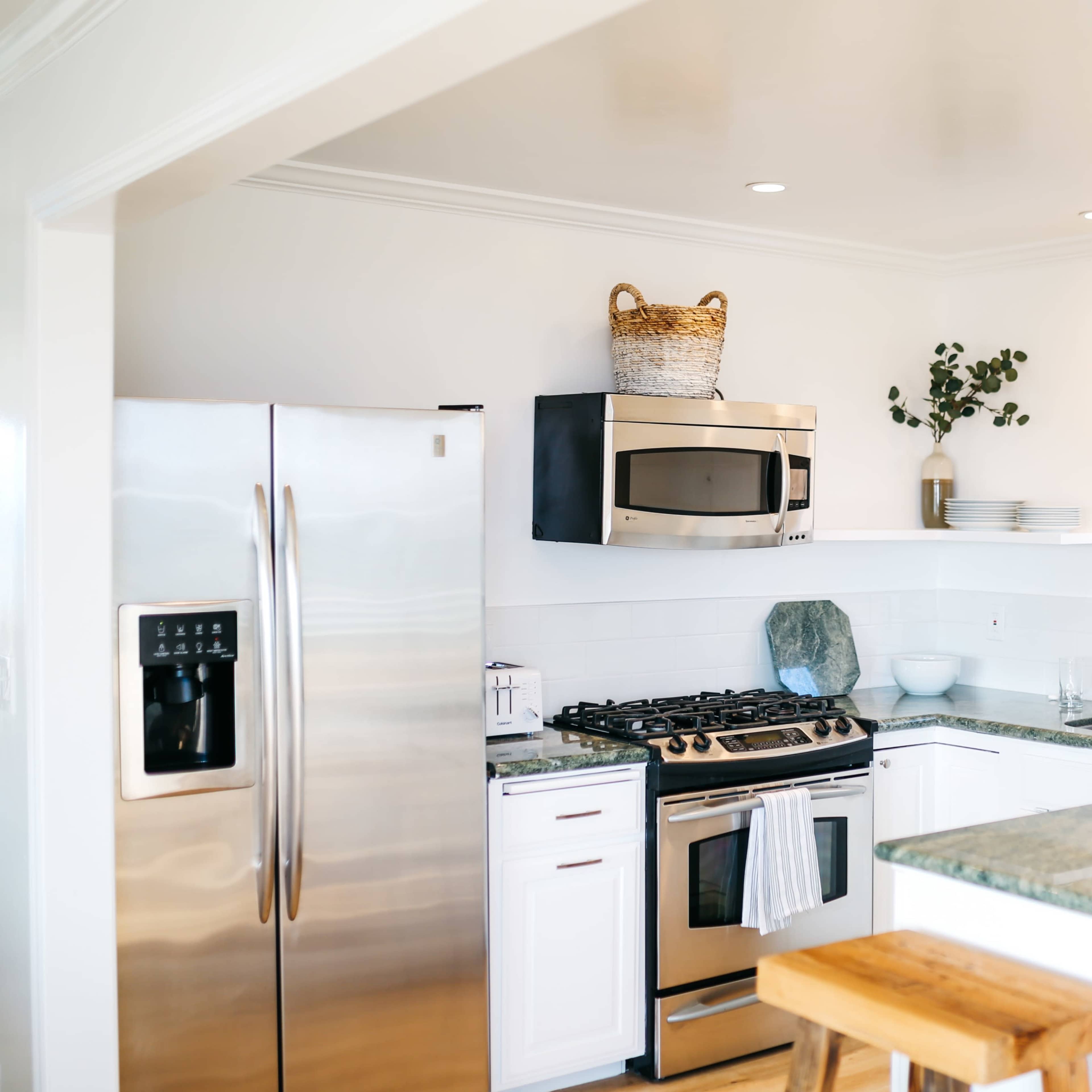 A modern kitchen features stainless steel appliances, white cabinetry, and a green granite countertop.