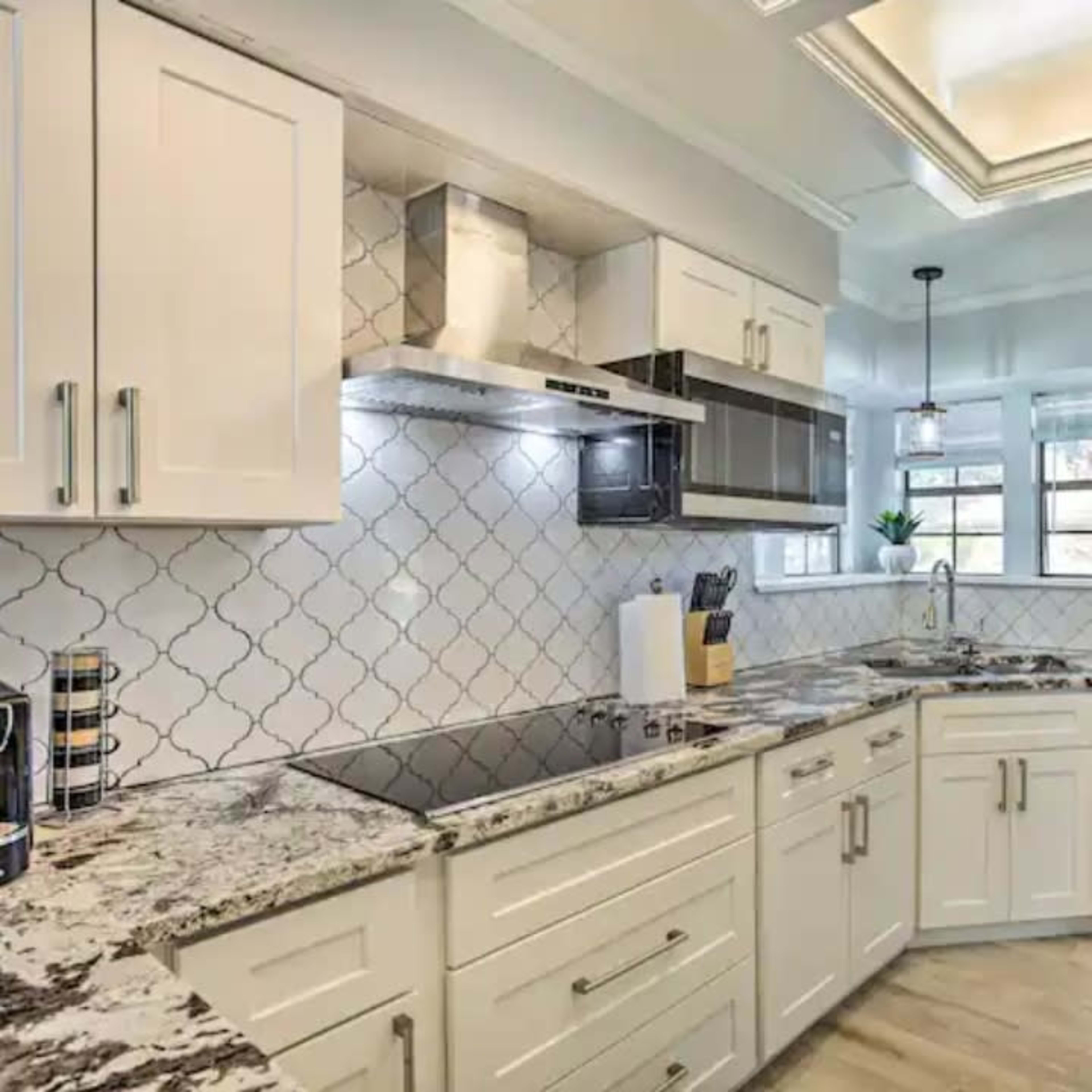 A modern kitchen with white cabinetry, a granite countertop, and stainless steel appliances.