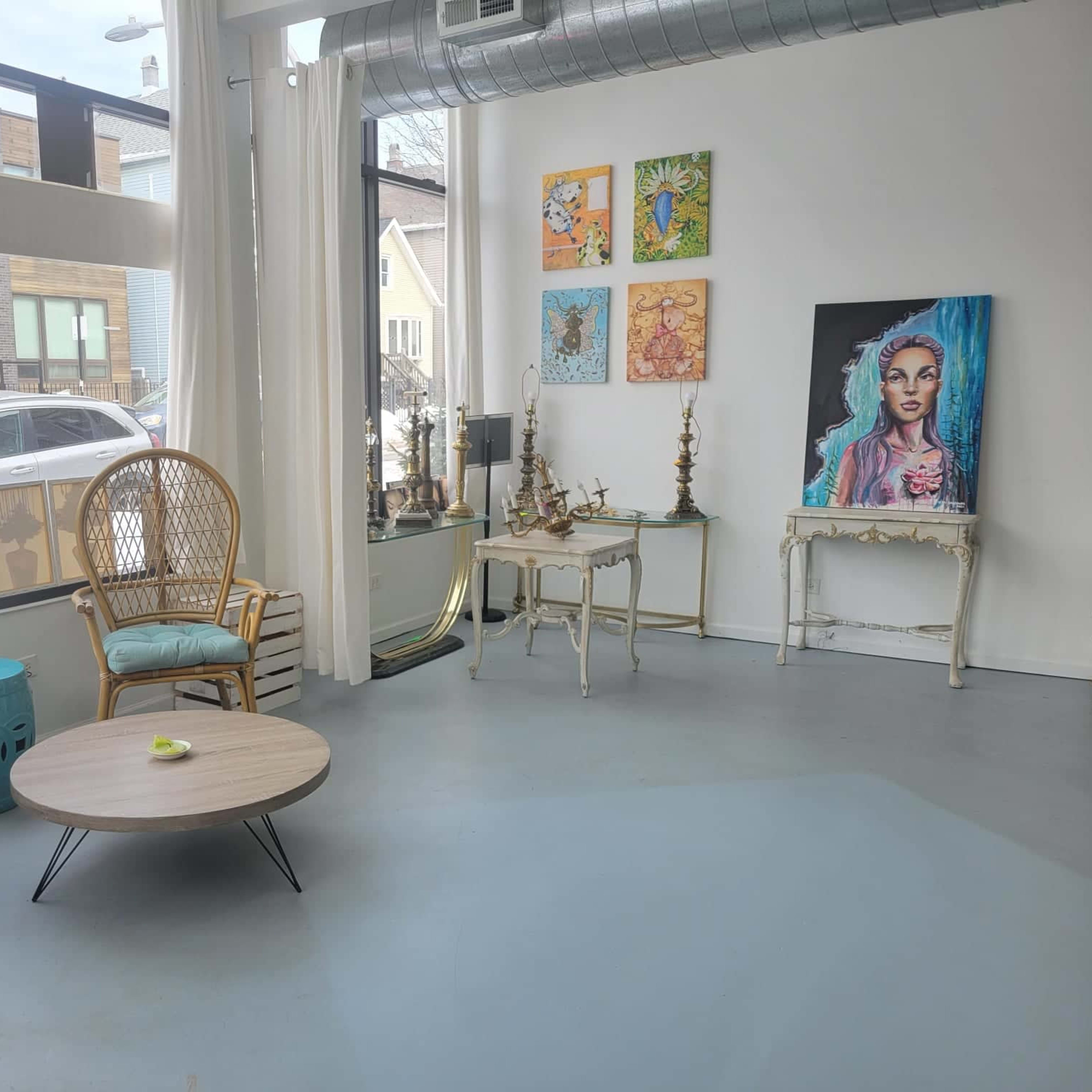 A spacious room with large windows, featuring two rattan chairs, a round table, and wall art, overlooking a snowy outdoor scene.