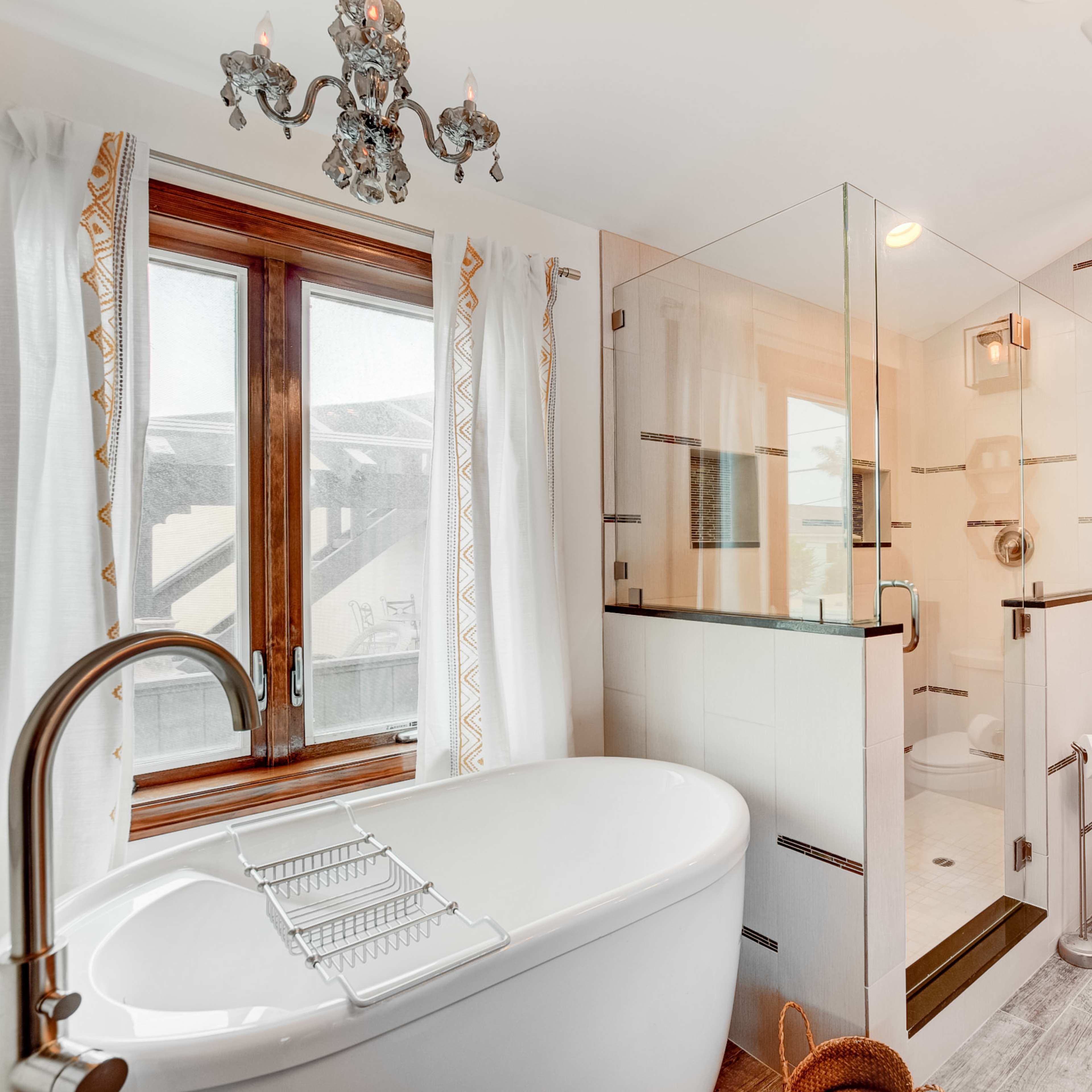 The bathroom features a freestanding bathtub, a glass shower enclosure, a toilet, and modern cabinetry with a dark countertop.