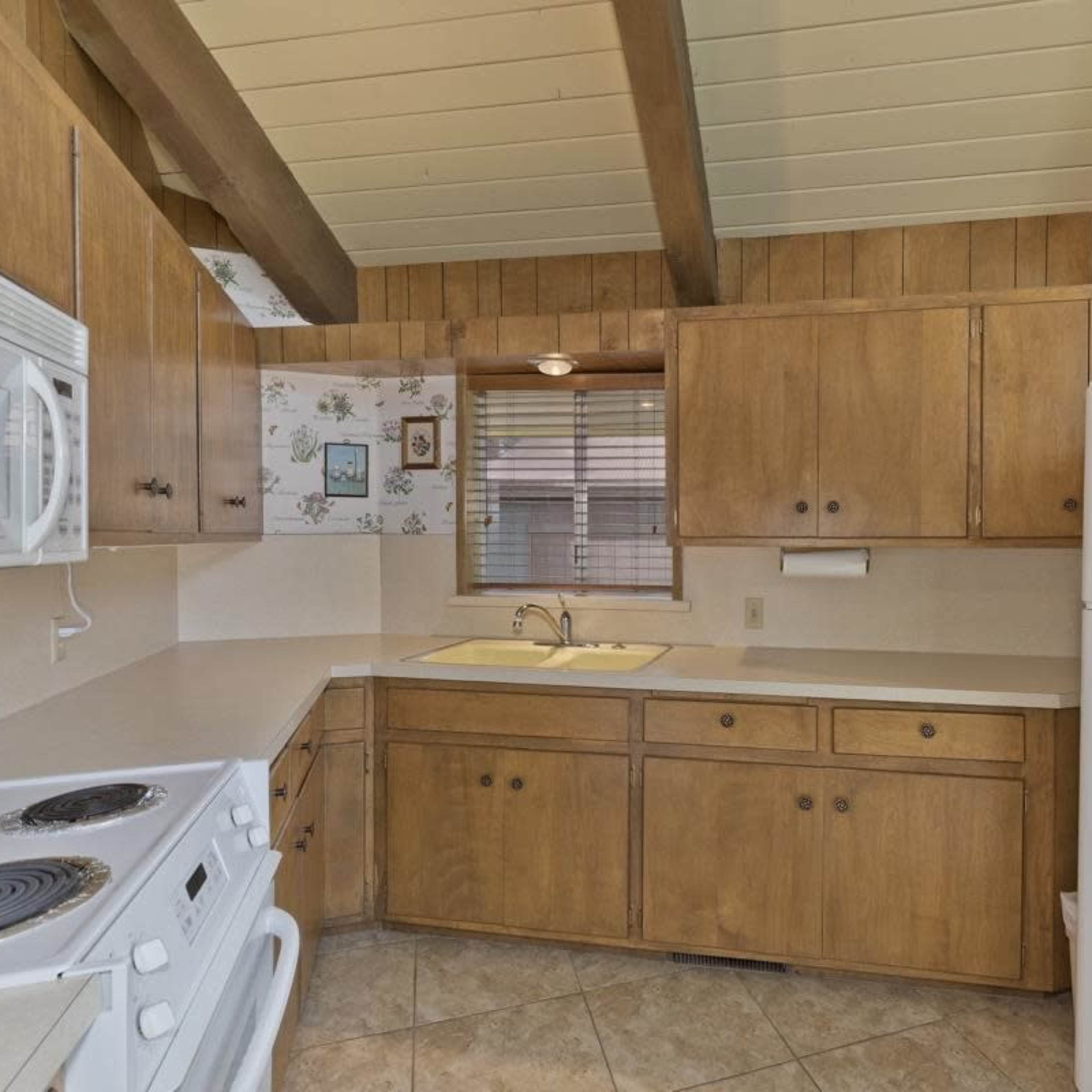 A kitchen with wooden cabinets, a white sink, and appliances including a stove and refrigerator.