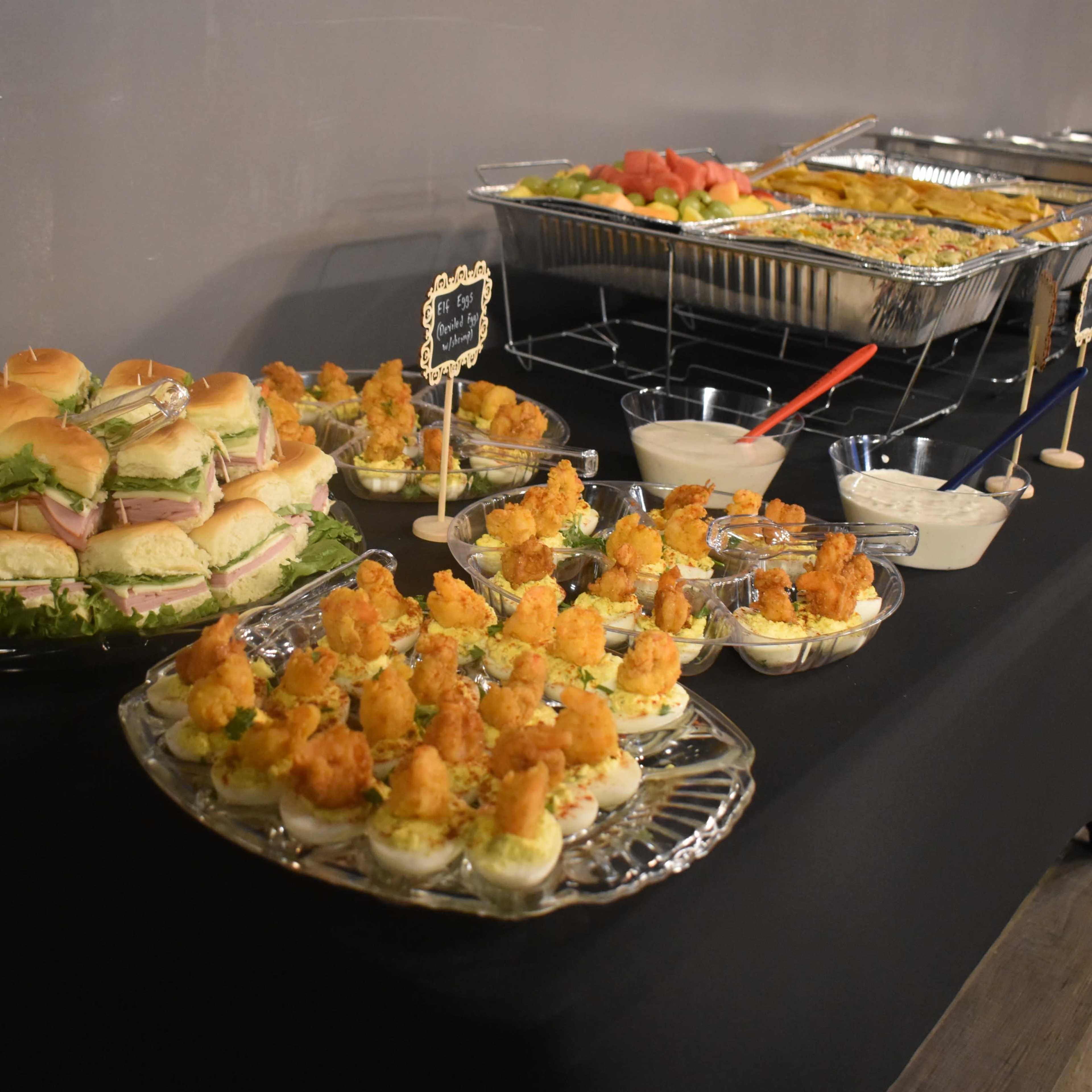 A buffet table featuring trays of sandwiches, shrimp cocktails, and assorted appetizers.