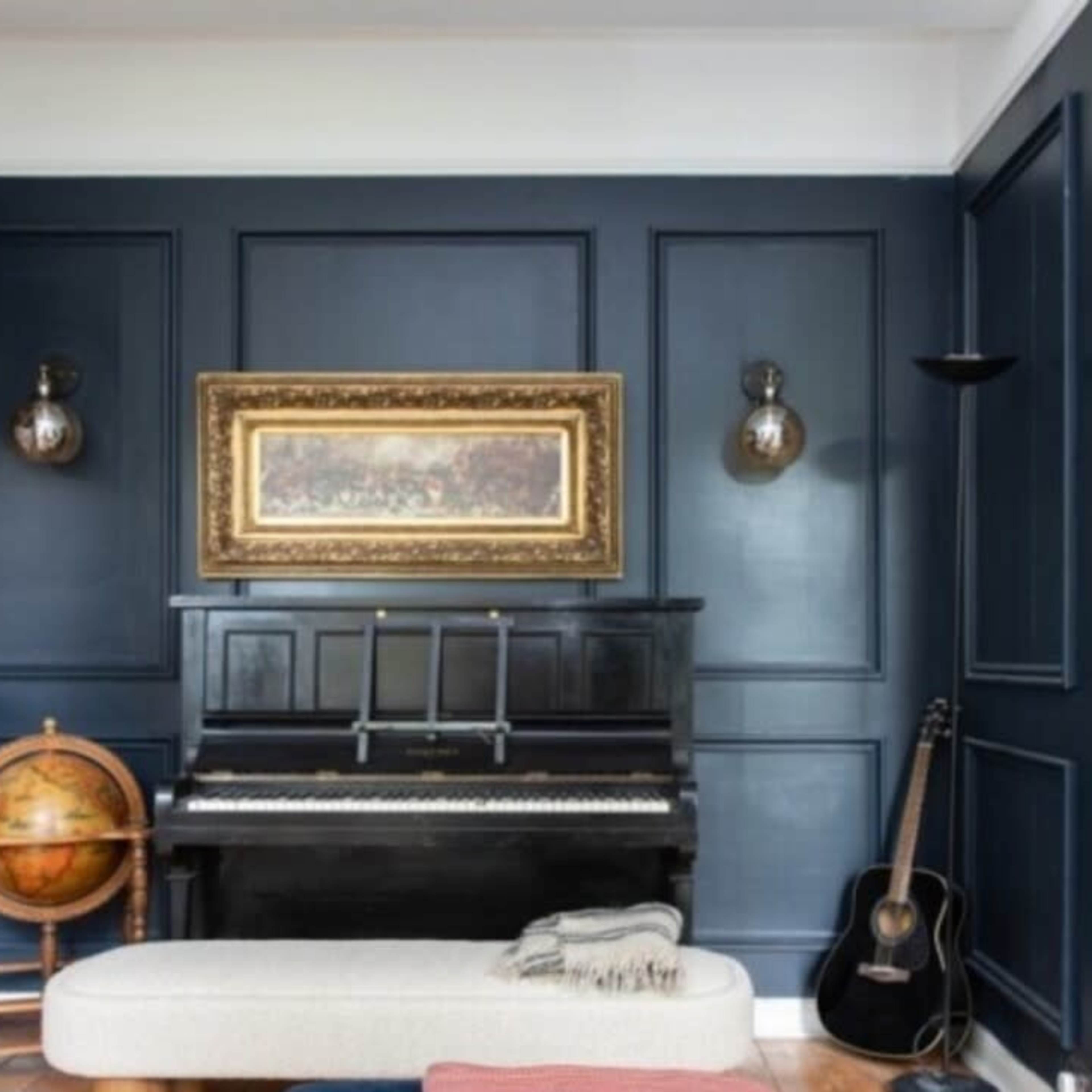 A cozy living room featuring a black upright piano, a globe on a wooden stand, and a guitar leaning against the wall, with dark blue paneled walls and a framed painting.