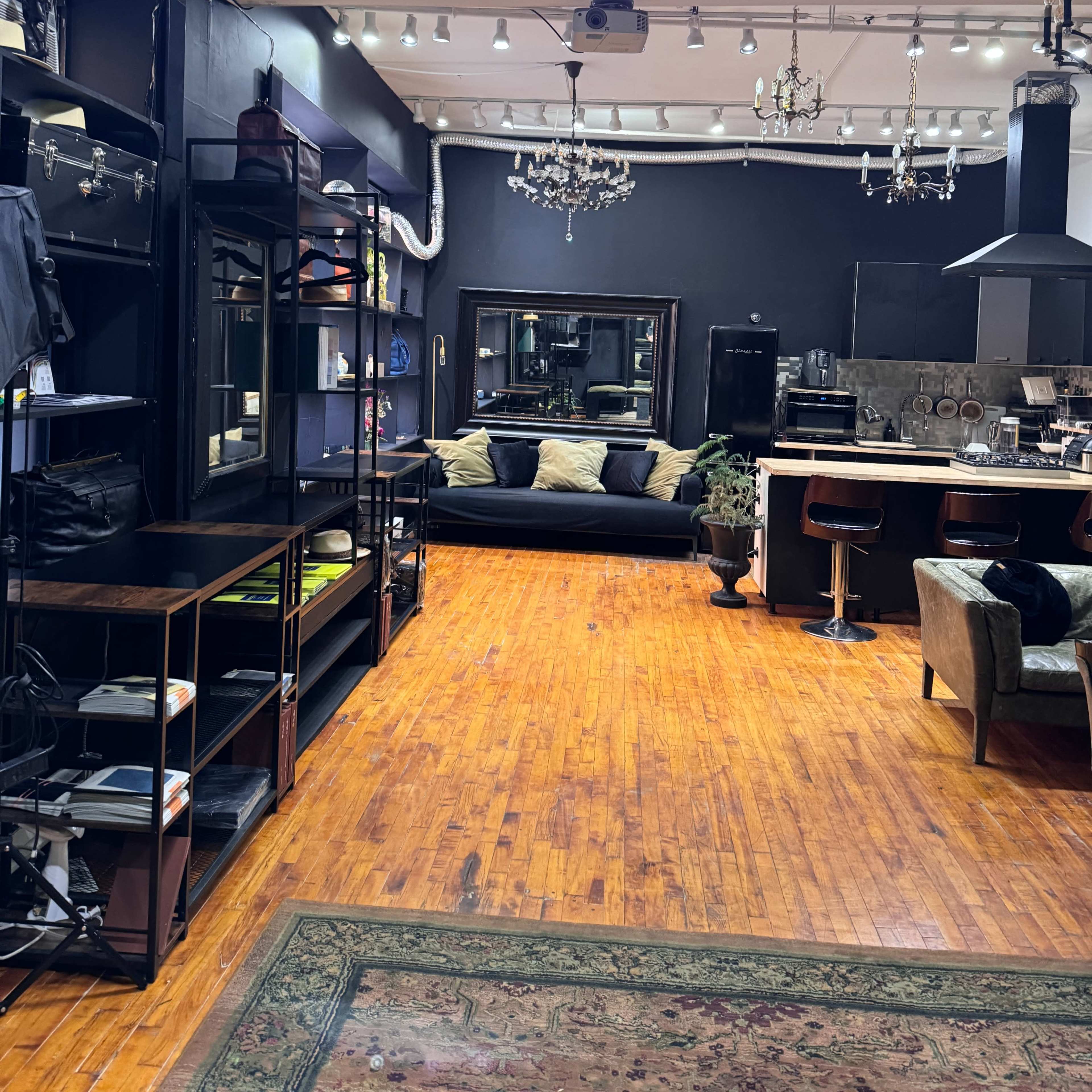 A stylish boutique interior featuring shelving units, a black sofa with cushions, and various light fixtures hanging from the ceiling.